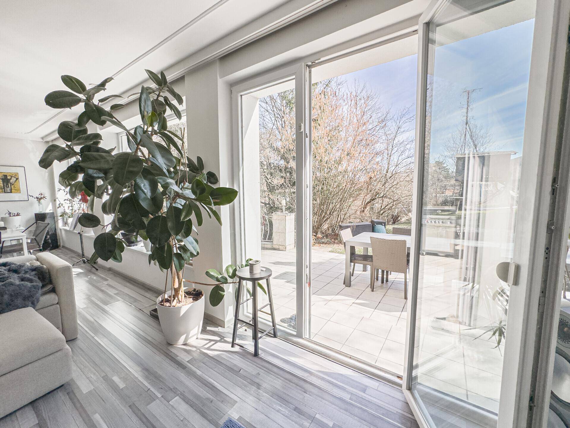 Helles Wohnzimmer mit großen Glasfronten und direktem Zugang zur Außenterrasse.