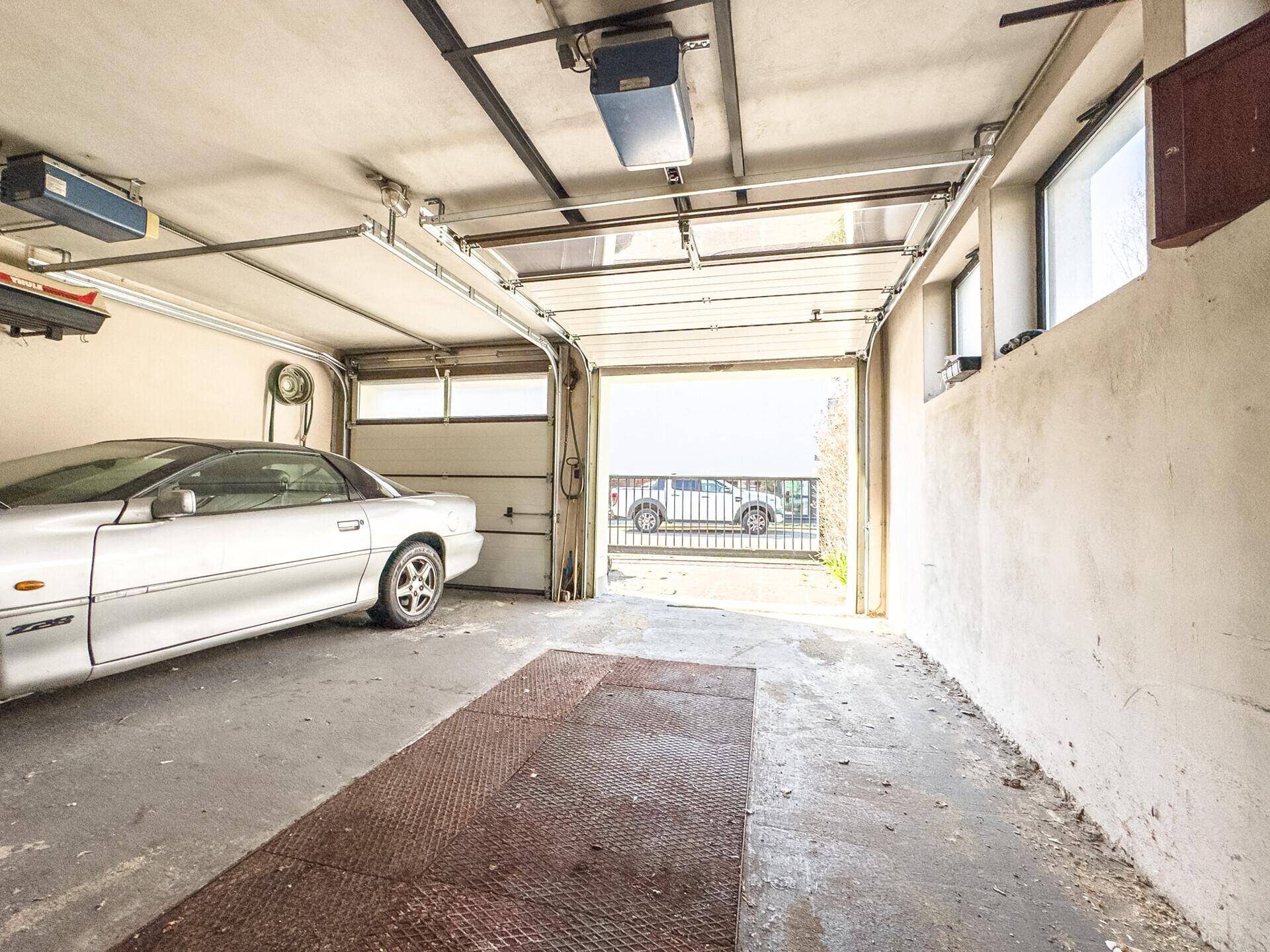 Geräumige Garage mit einem geparkten Auto und offenem Garagentor.