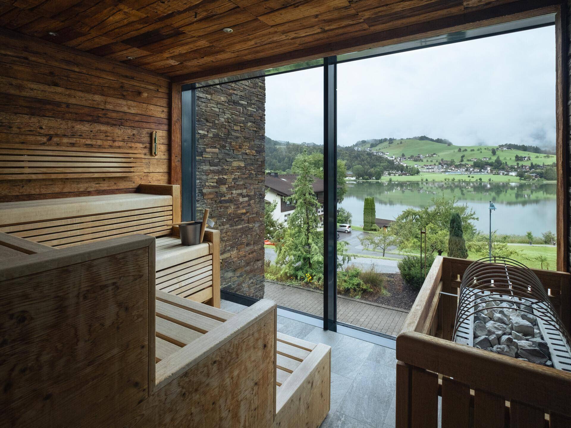 Holzvertäfelte Sauna mit großen Fenstern und entspannendem Blick auf den See und die Landschaft.