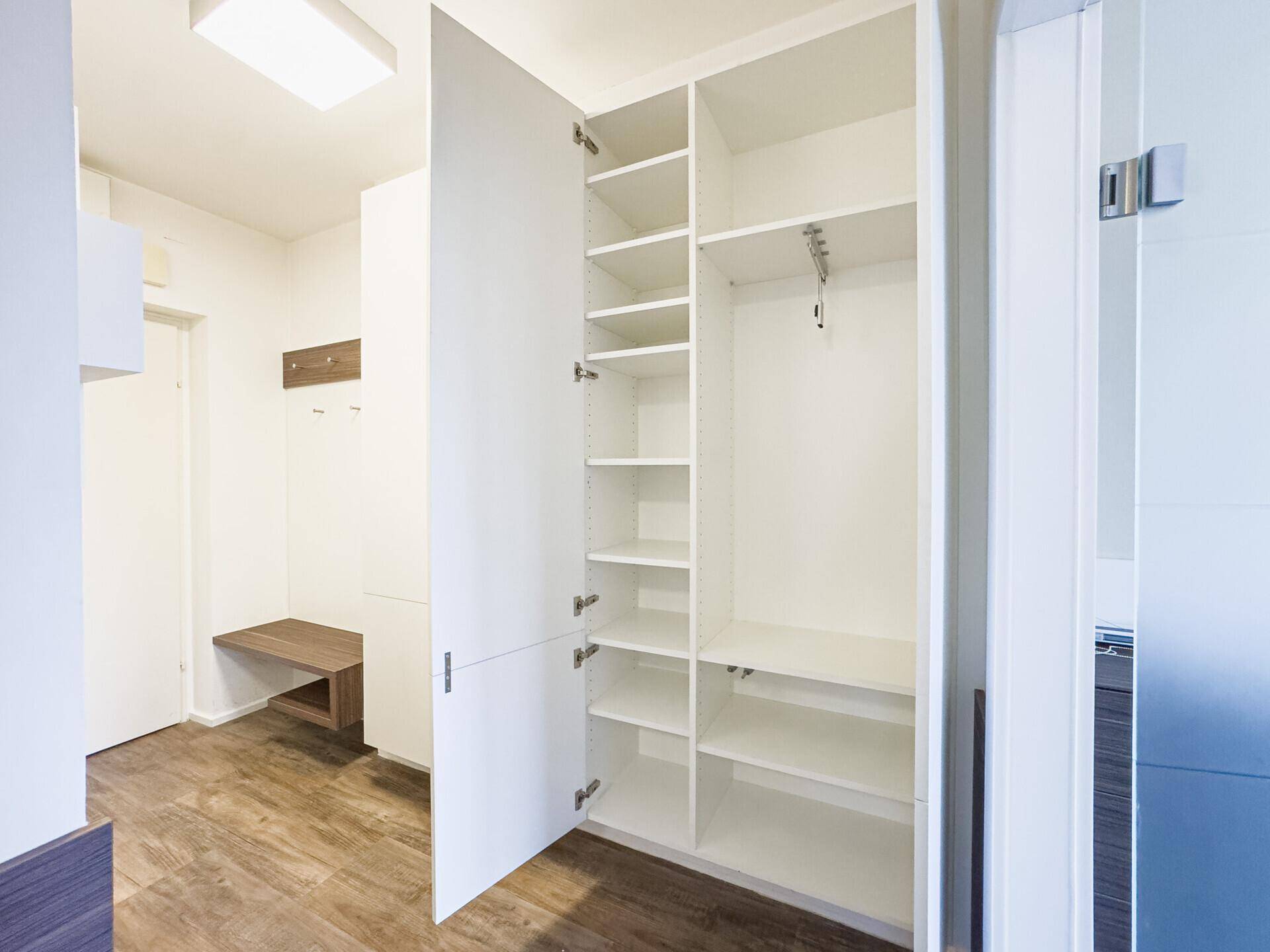 Praktischer Einbauschrank im Eingangsbereich mit viel Stauraum und offenen Regalen.