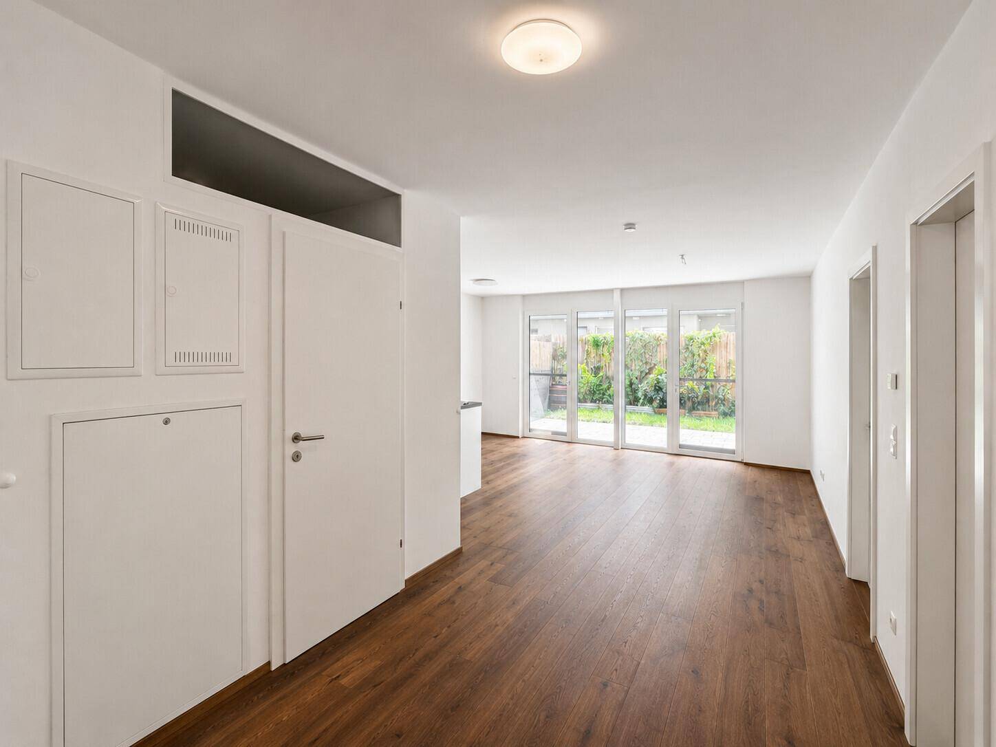 Heller Eingangsbereich mit Holzboden, der in den offenen Wohnbereich führt.