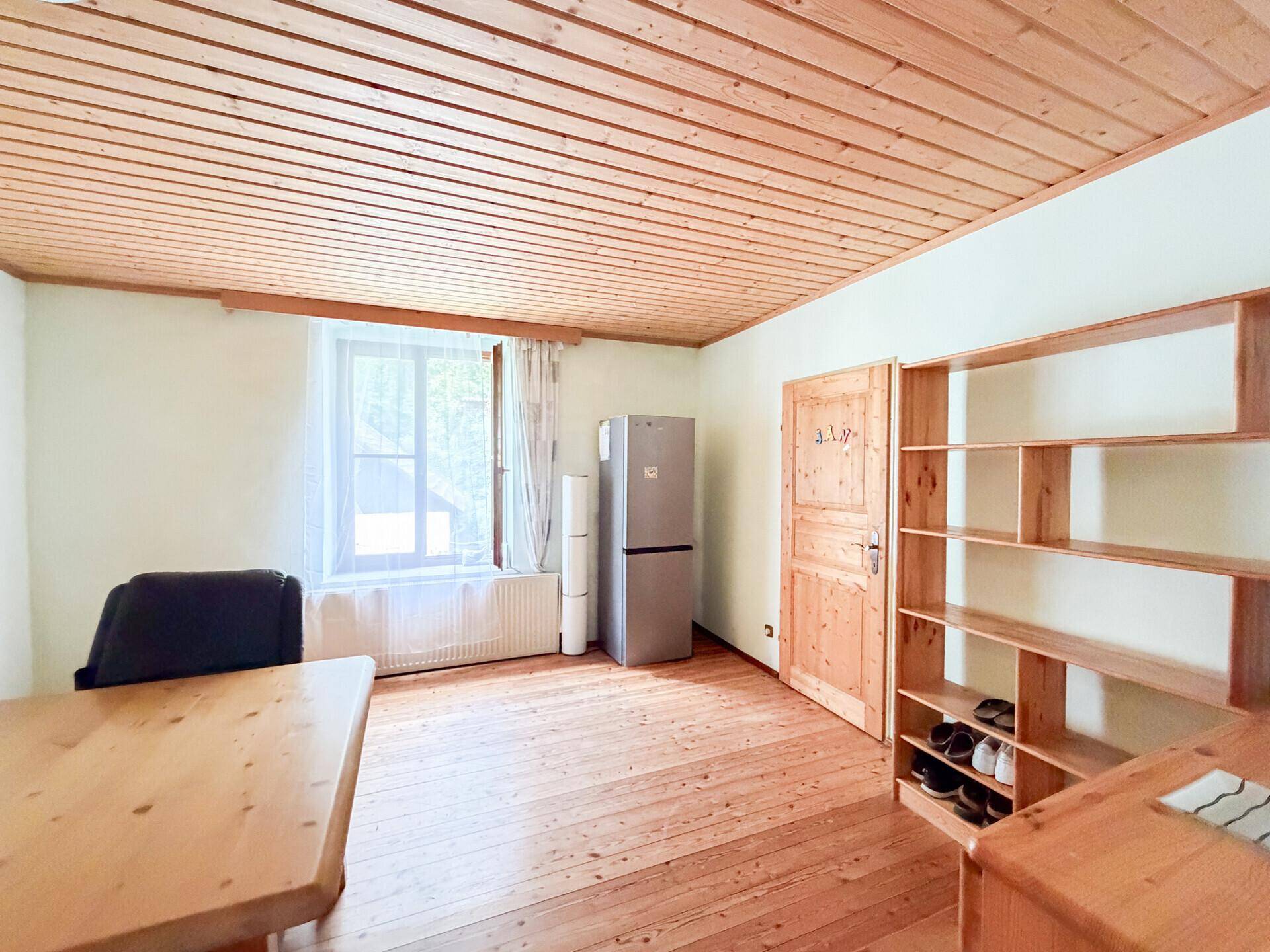 Geräumiges Zimmer mit Holzdielenboden, Holzdecke und Holzmöbeln.
