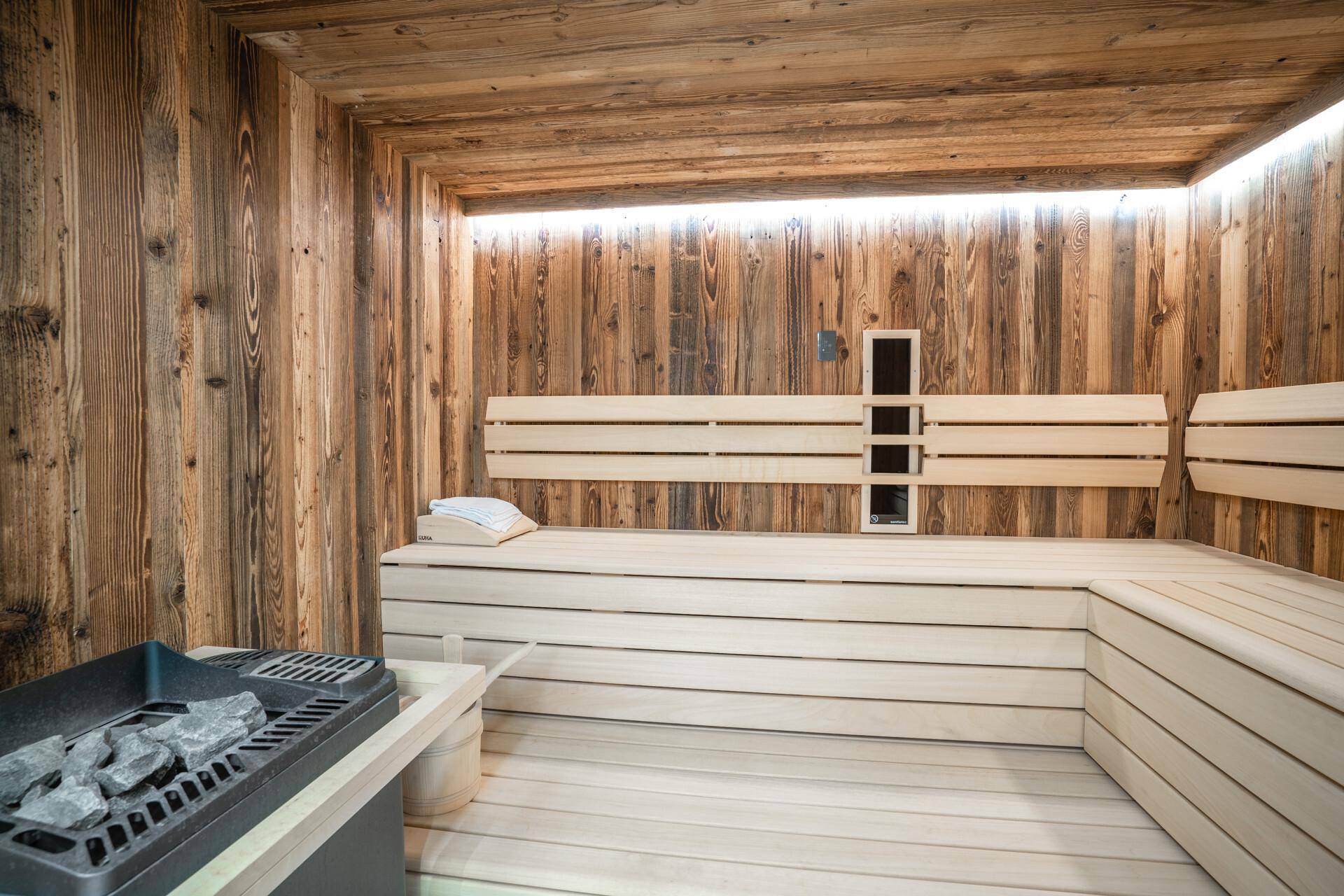 Geräumige Holzsauna mit bequemen Bänken und traditionellem Saunaofen für Entspannung.