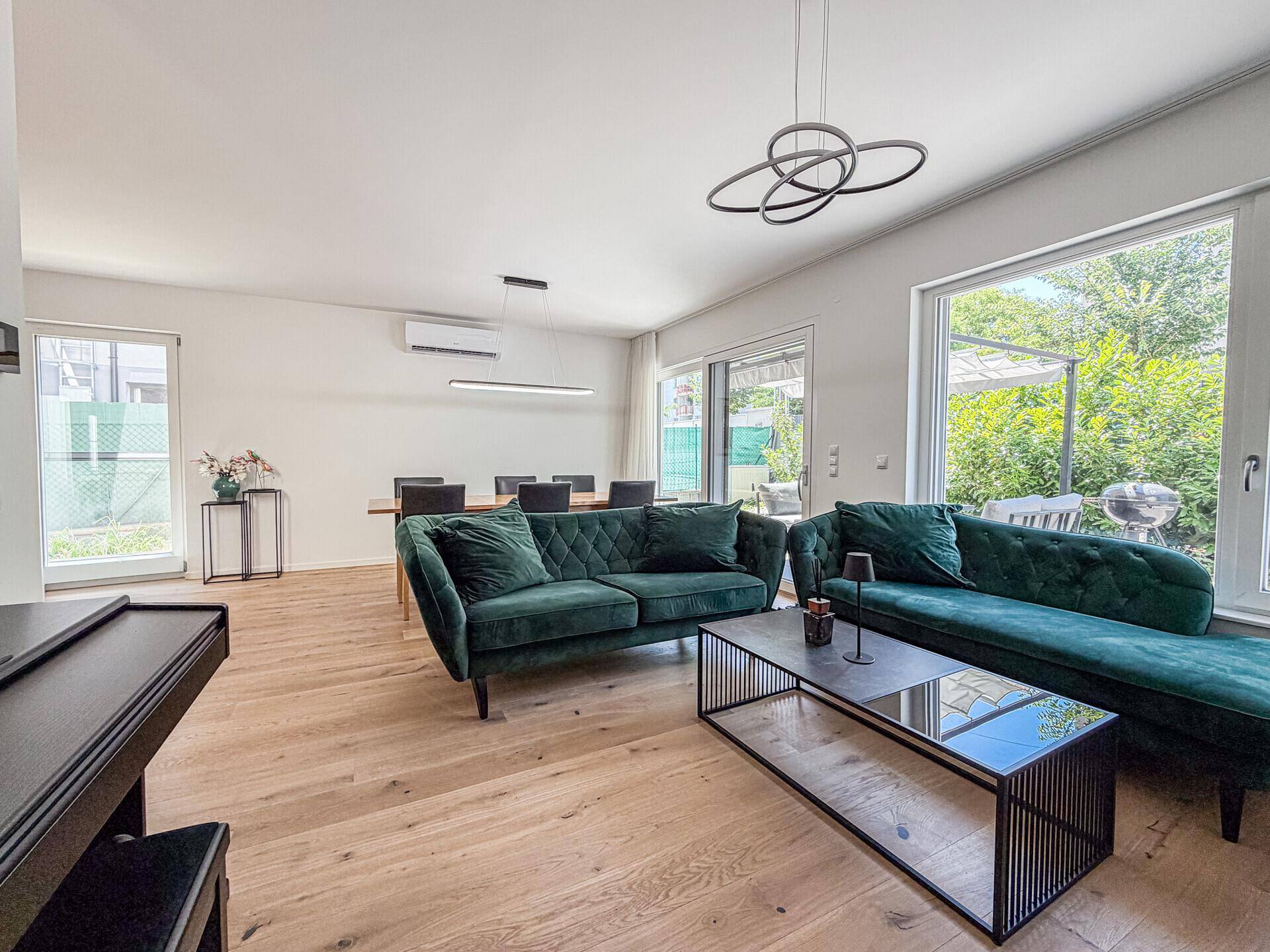Gemütliches Wohnzimmer mit großen Fenstern, bequemen Sofas und Zugang zur Terrasse.