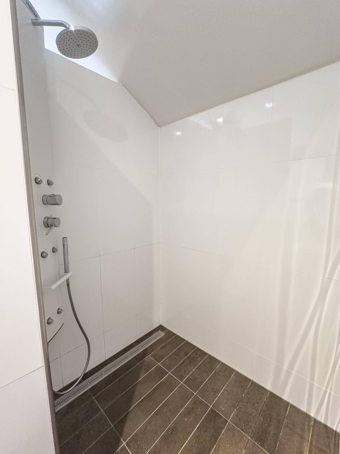 Geräumige begehbare Dusche mit Regenduschkopf und modernen Fliesen.