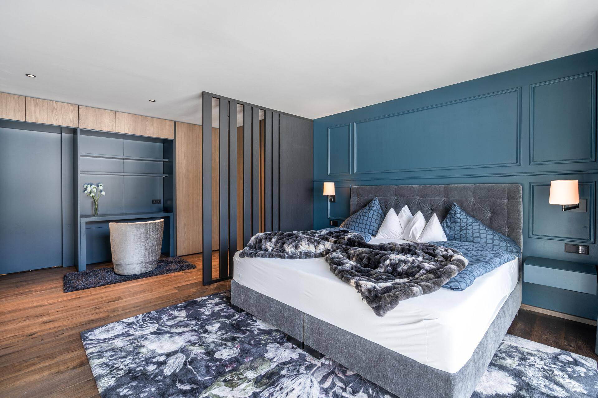 Stilvolles Schlafzimmer mit blauer Akzentwand, Holzboden und integriertem Ankleidebereich.