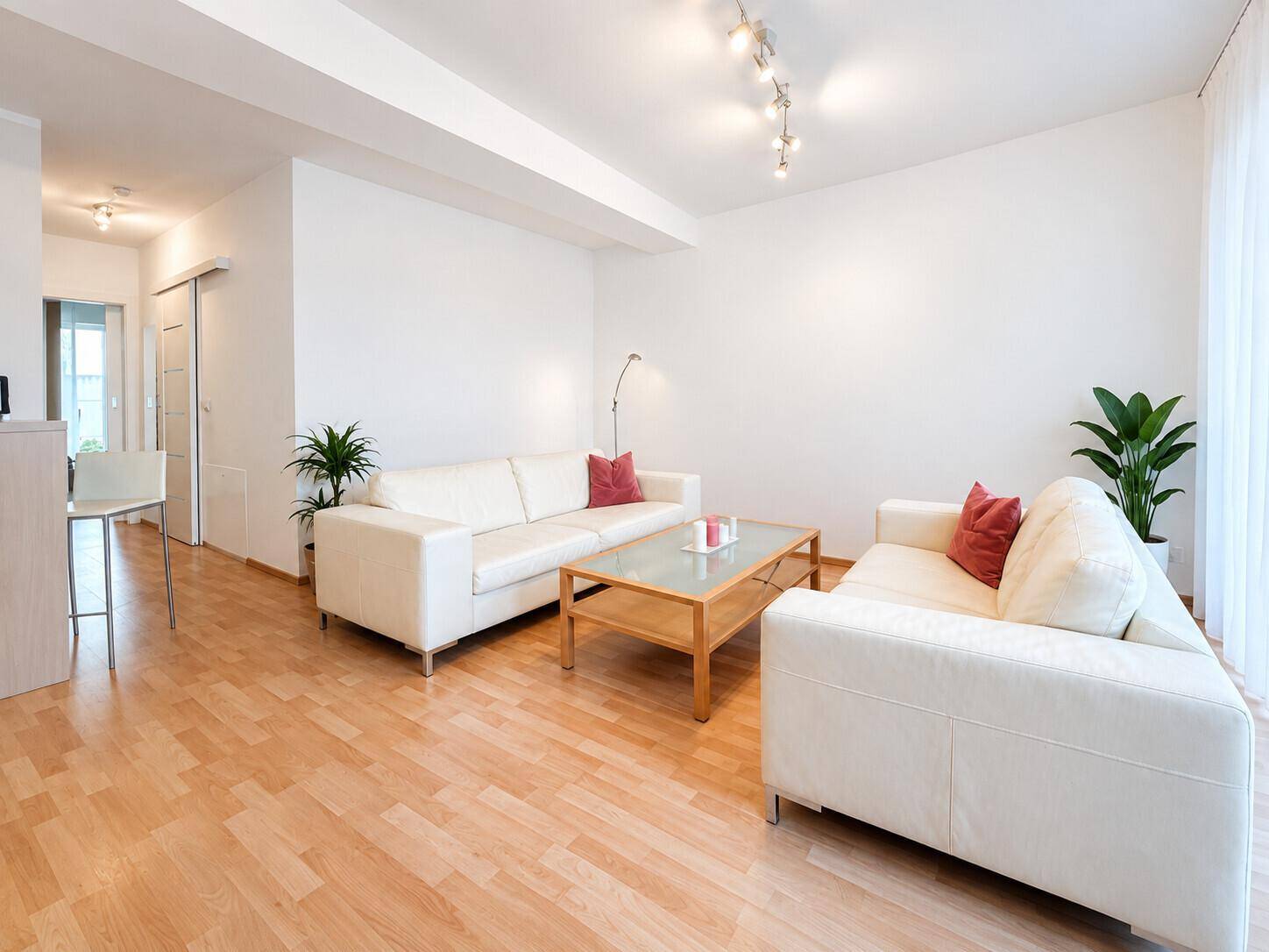 Geräumiges Wohnzimmer mit bequemen Sofas, Holzboden und schlichter, moderner Einrichtung.