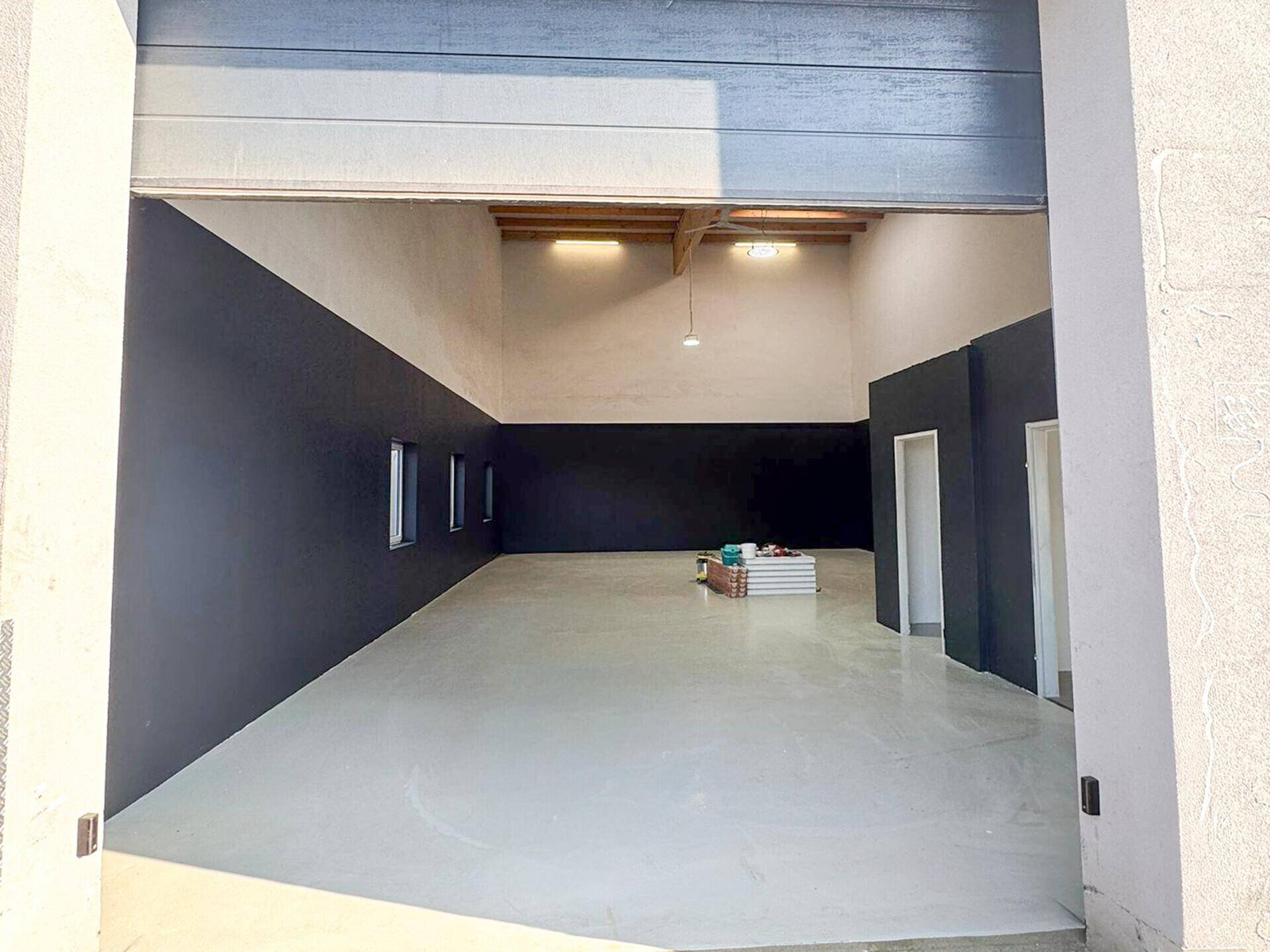 Helle und geräumige Garage mit hohen Decken, Holzbalken und einem großen Eingangstor.