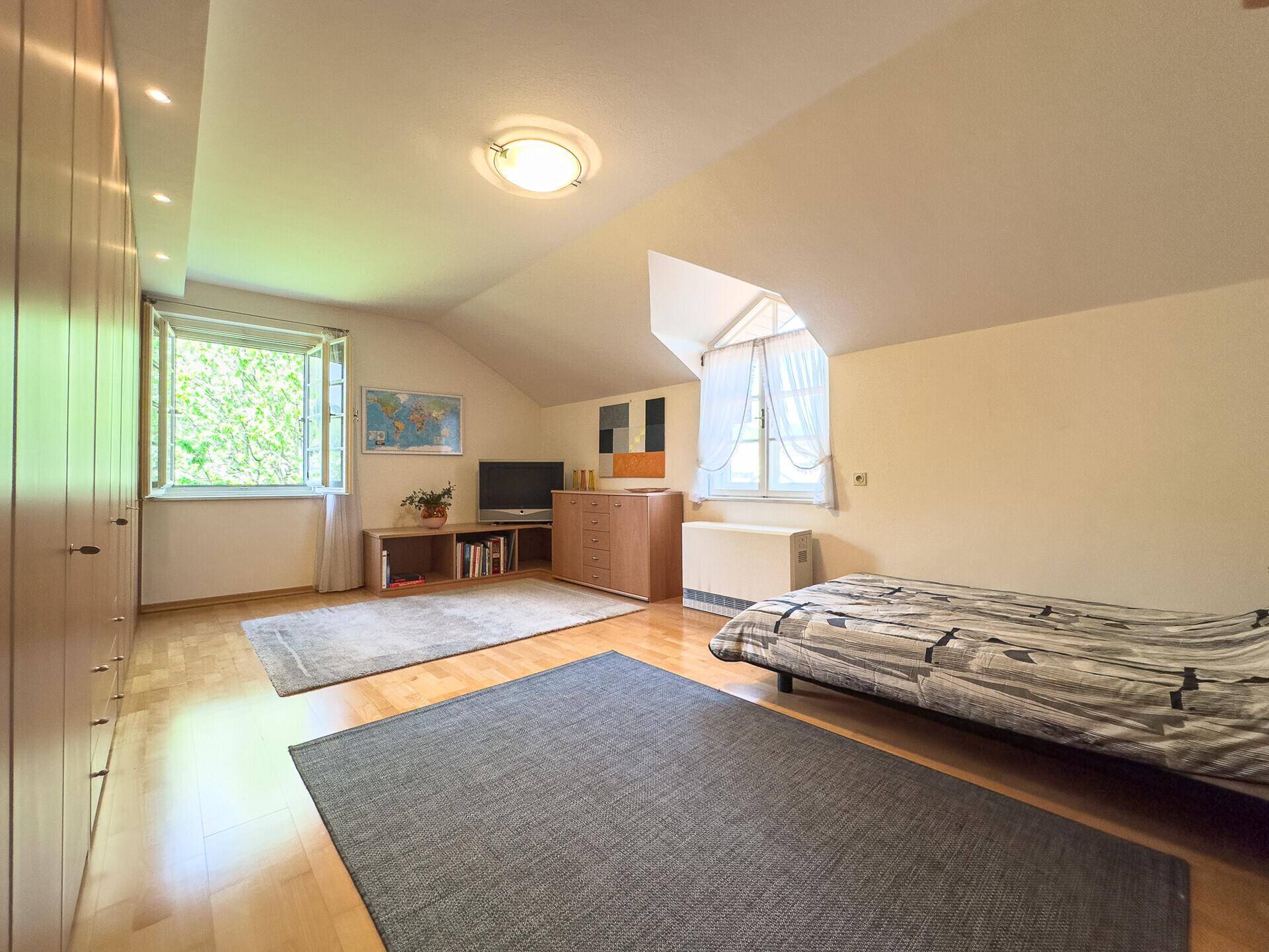 Kinderzimmer oder Gästezimmer mit Holzboden, Schrankwand und Dachschräge.