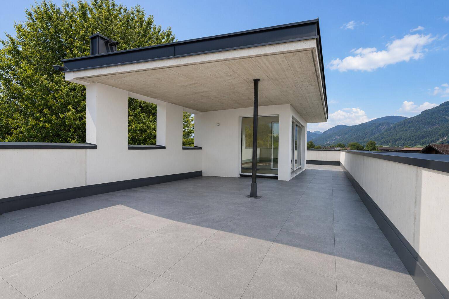 Geräumige Dachterrasse mit Fliesenboden und weitem Blick auf die Berge und die Landschaft.
