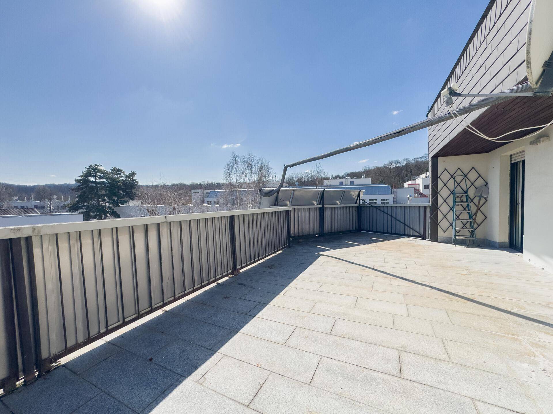 Geräumige Dachterrasse mit Fliesenboden und weitem Blick über die Umgebung.