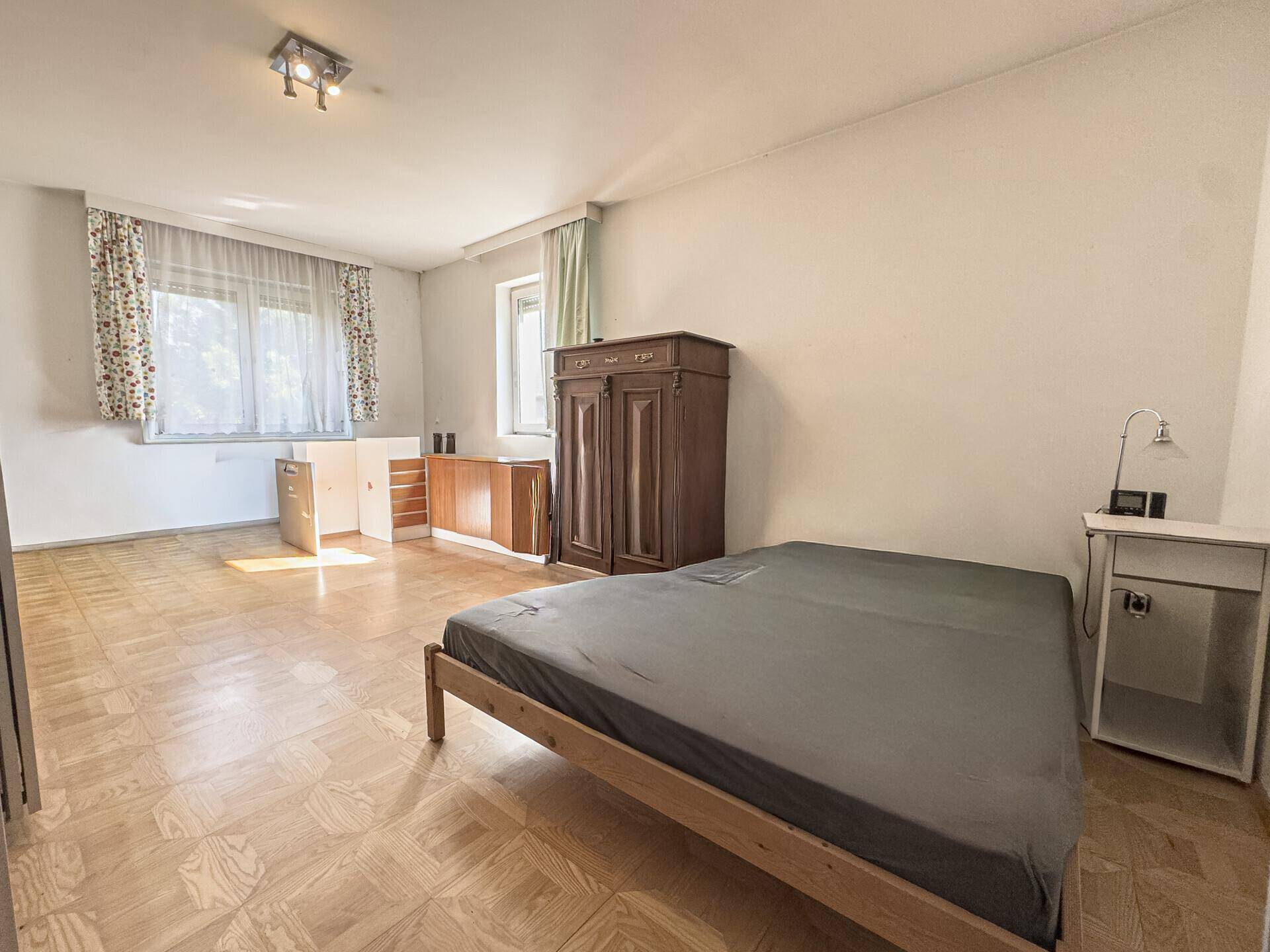 Schlafzimmer mit Parkettboden, einem Bett und einem kleinen Küchenbereich.