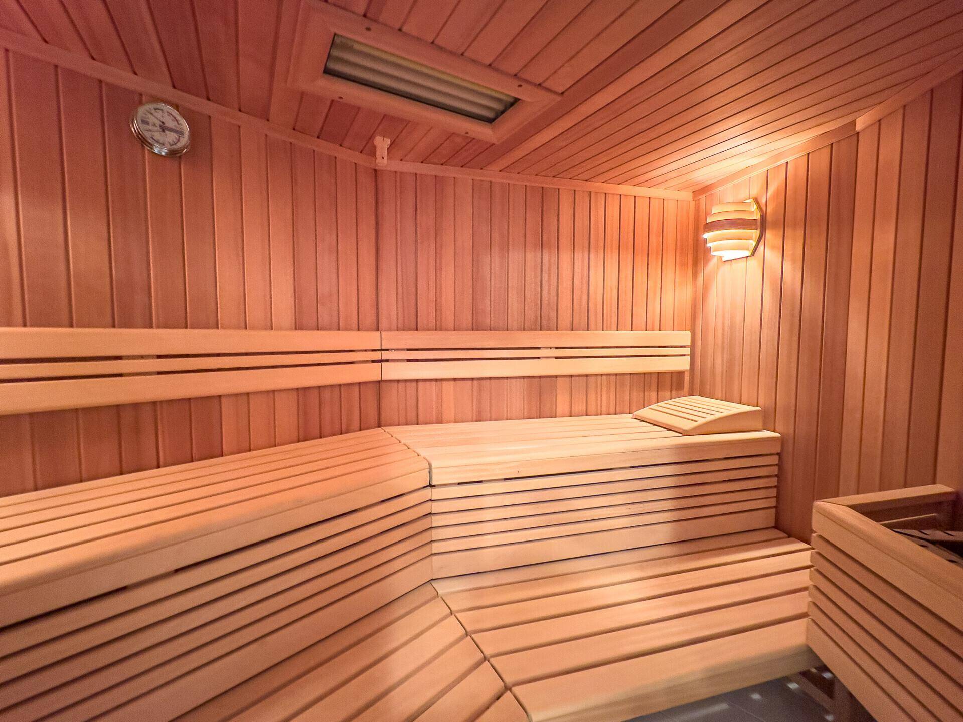 Gemütliche Holzsauna mit Bänken und traditionellem Ofen für Entspannung.