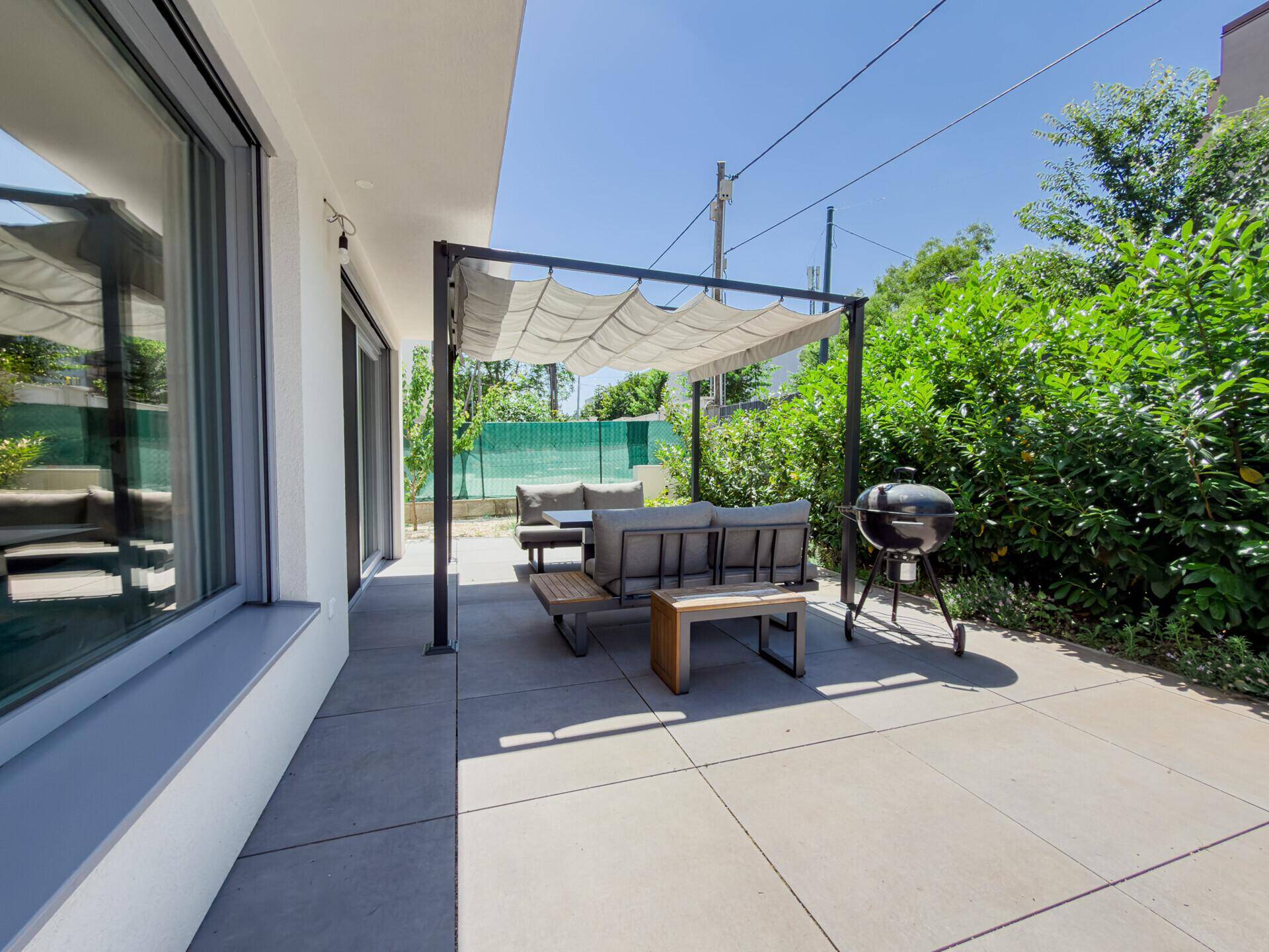 Gemütliche Terrasse mit Pergola, Gartenmöbeln und Grillbereich, ideal für entspannte Stunden.