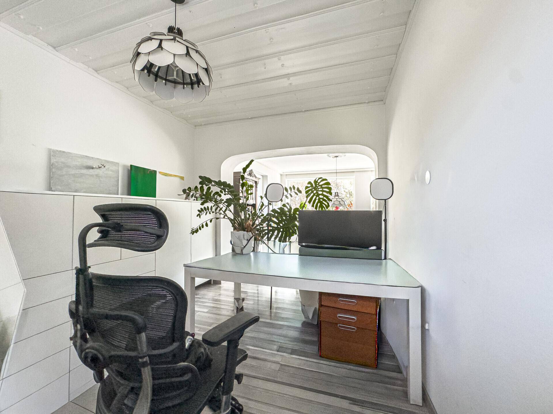 Funktionaler Arbeitsbereich mit Schreibtisch, Bürostuhl und Blick auf den offenen Wohnbereich.