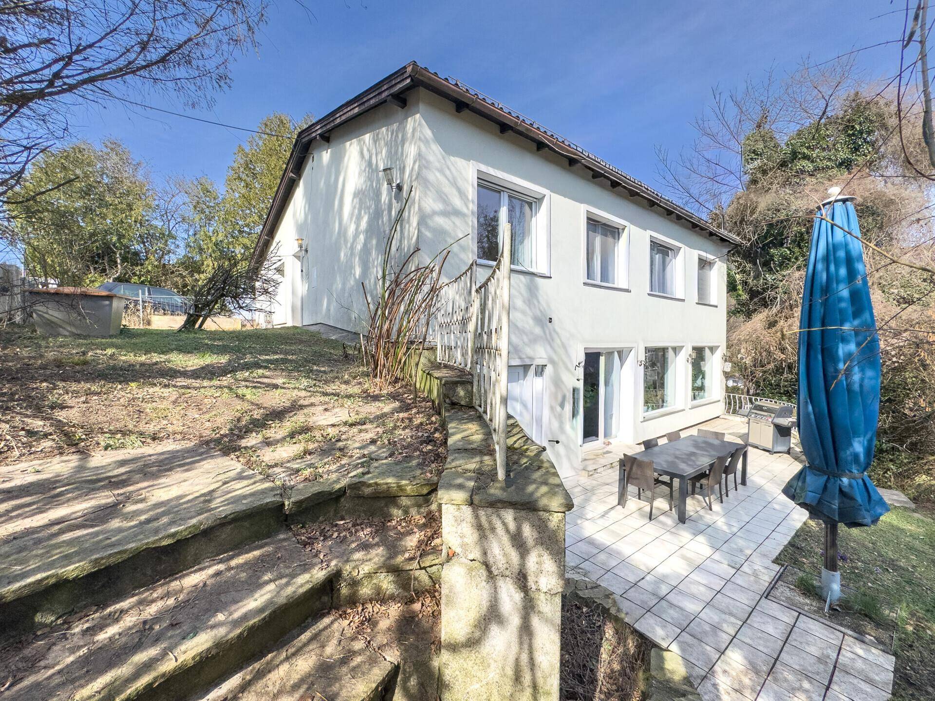 Ansicht des Hauses von der Seite mit Terrasse, Garten und Steintreppe.