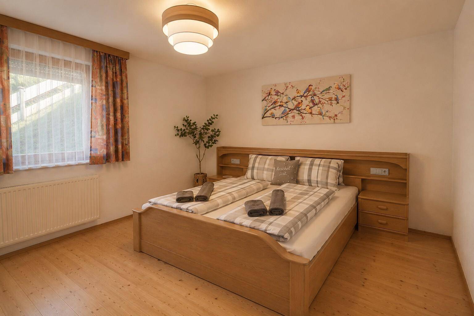 Gemütliches Schlafzimmer mit Holzdoppelbett, Nachttischen und Blick ins Grüne.