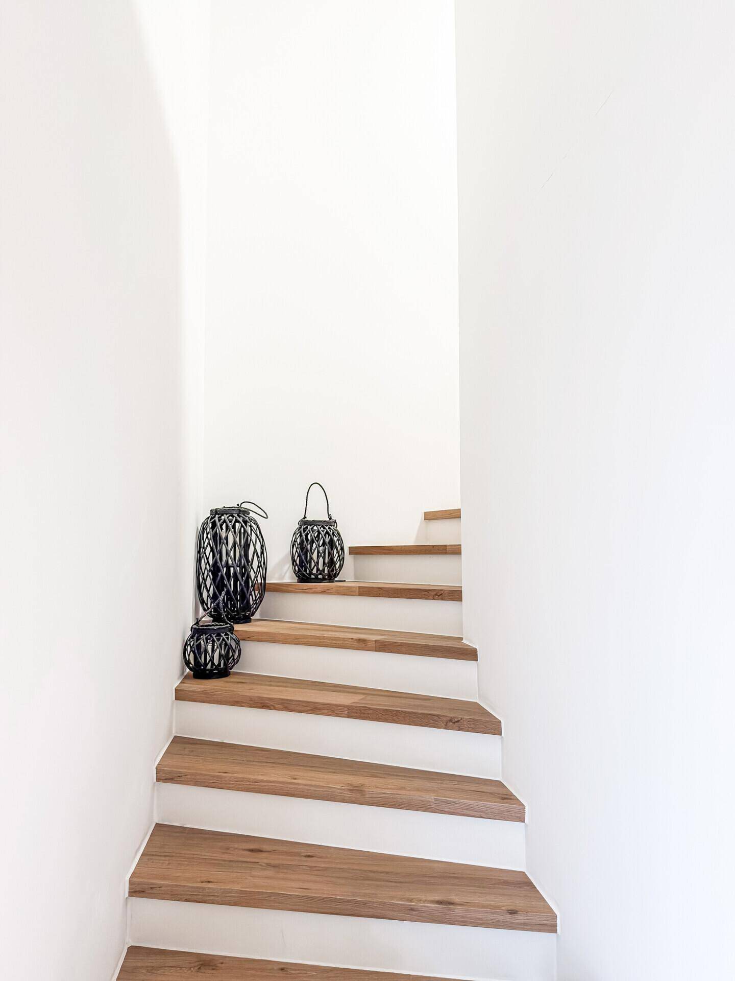Moderne Holztreppe mit weißen Setzstufen, die die verschiedenen Ebenen des Hauses elegant verbindet.