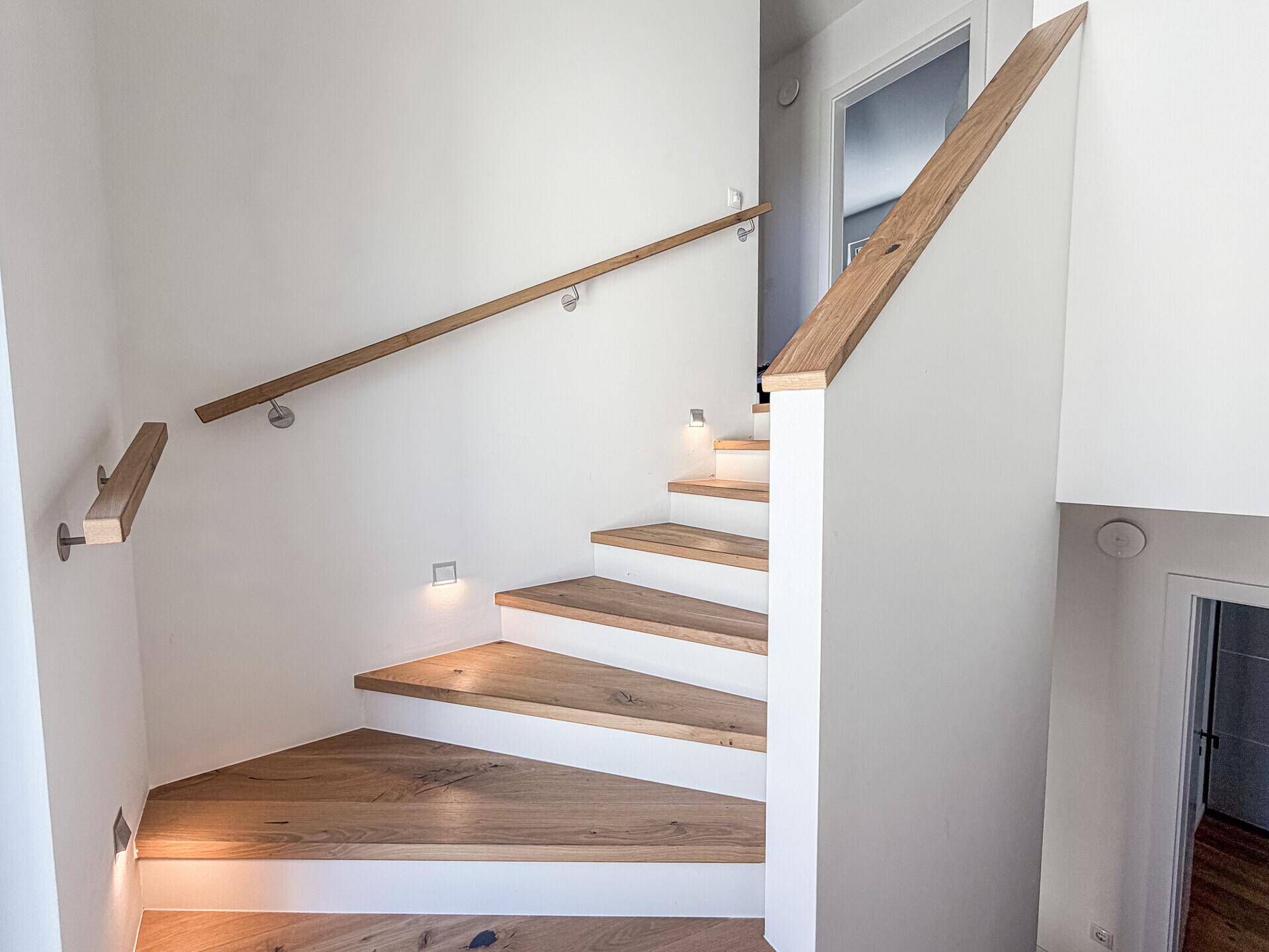 Elegante Holztreppe mit modernem Geländer und integrierter Beleuchtung.