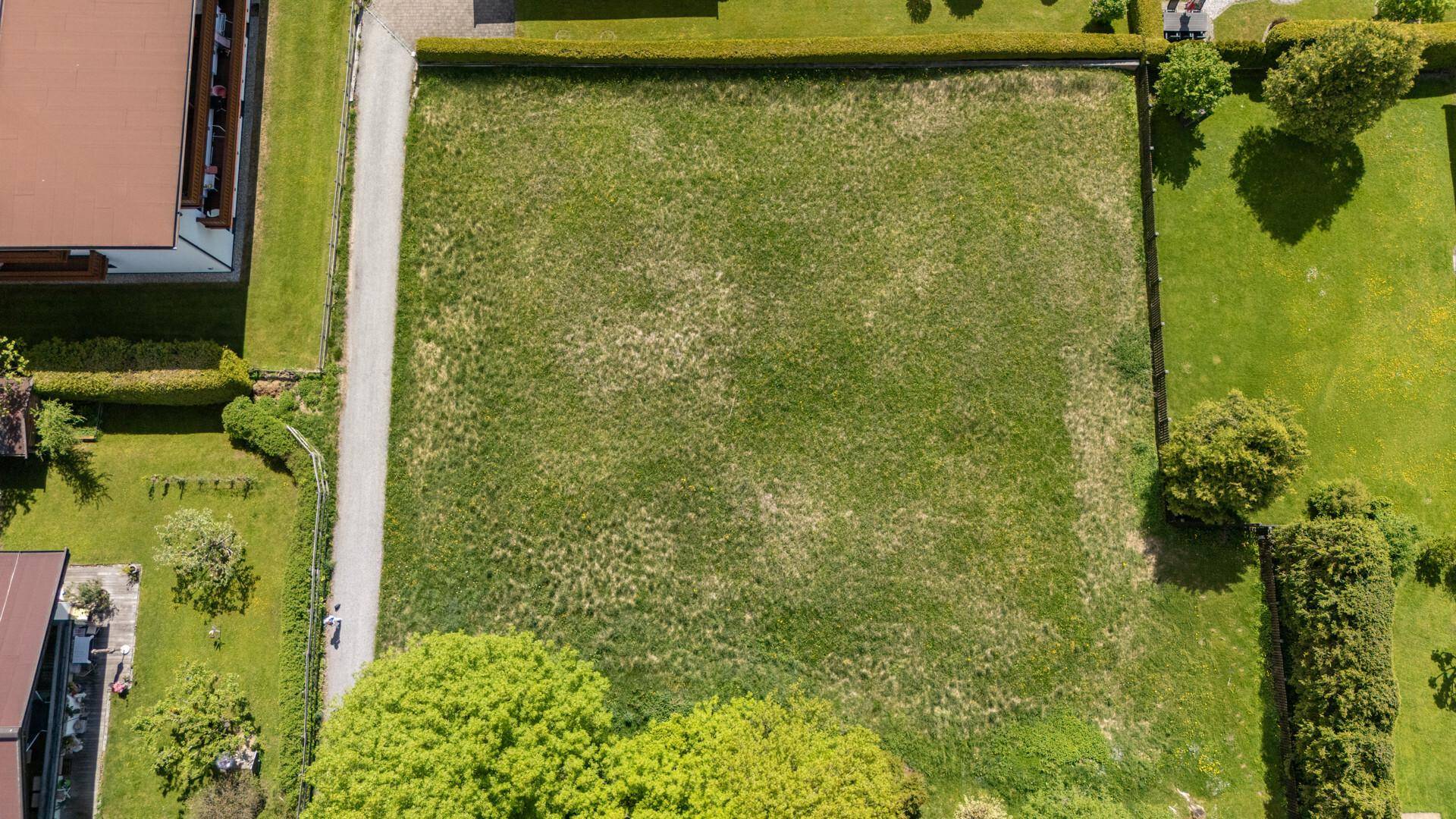 Luftaufnahme eines rechteckigen Grundstücks mit Rasenfläche und angrenzendem Schotterweg.