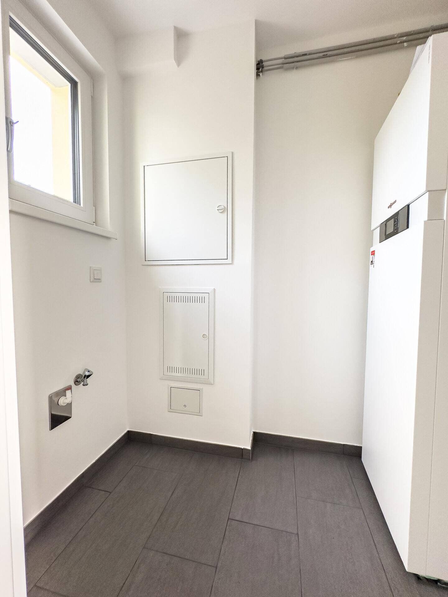 Hauswirtschaftsraum mit Heizungsanlage, Fenster und Anschlussmöglichkeiten.