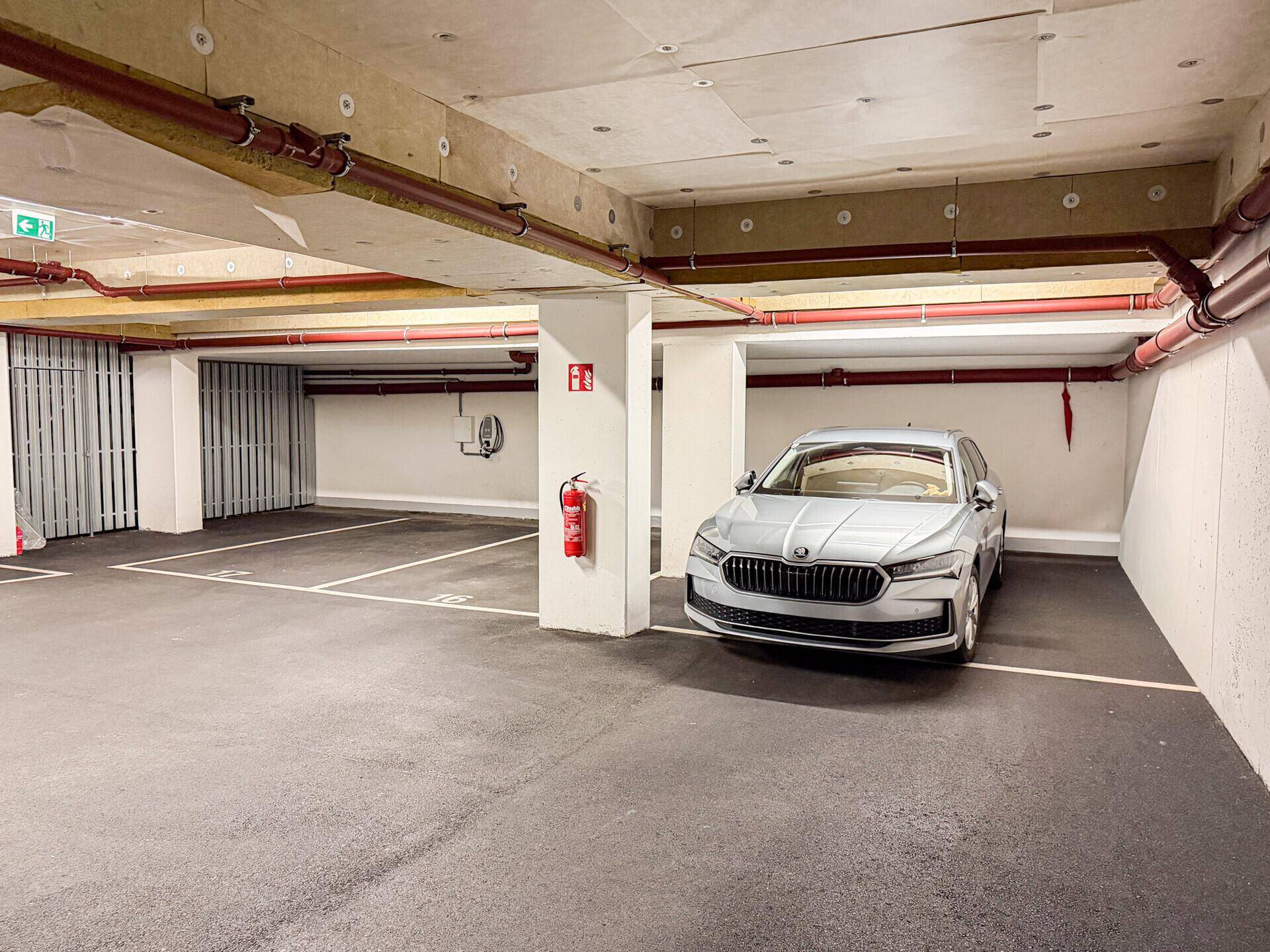 Tiefgarage mit markierten Stellplätzen und einem Elektrofahrzeug-Ladestation.