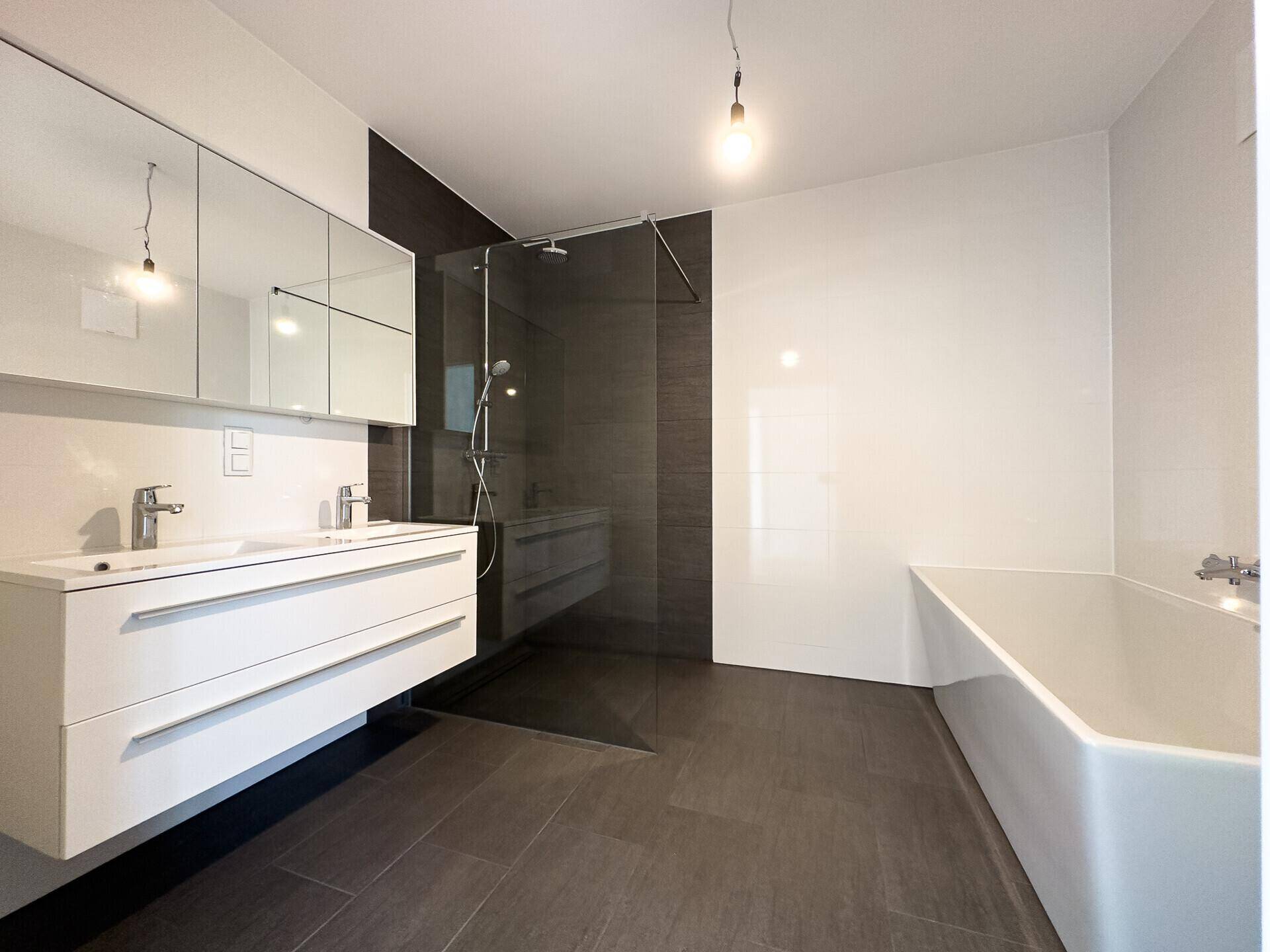 Modernes Badezimmer mit Doppelwaschbecken, begehbarer Dusche und eleganter Badewanne.