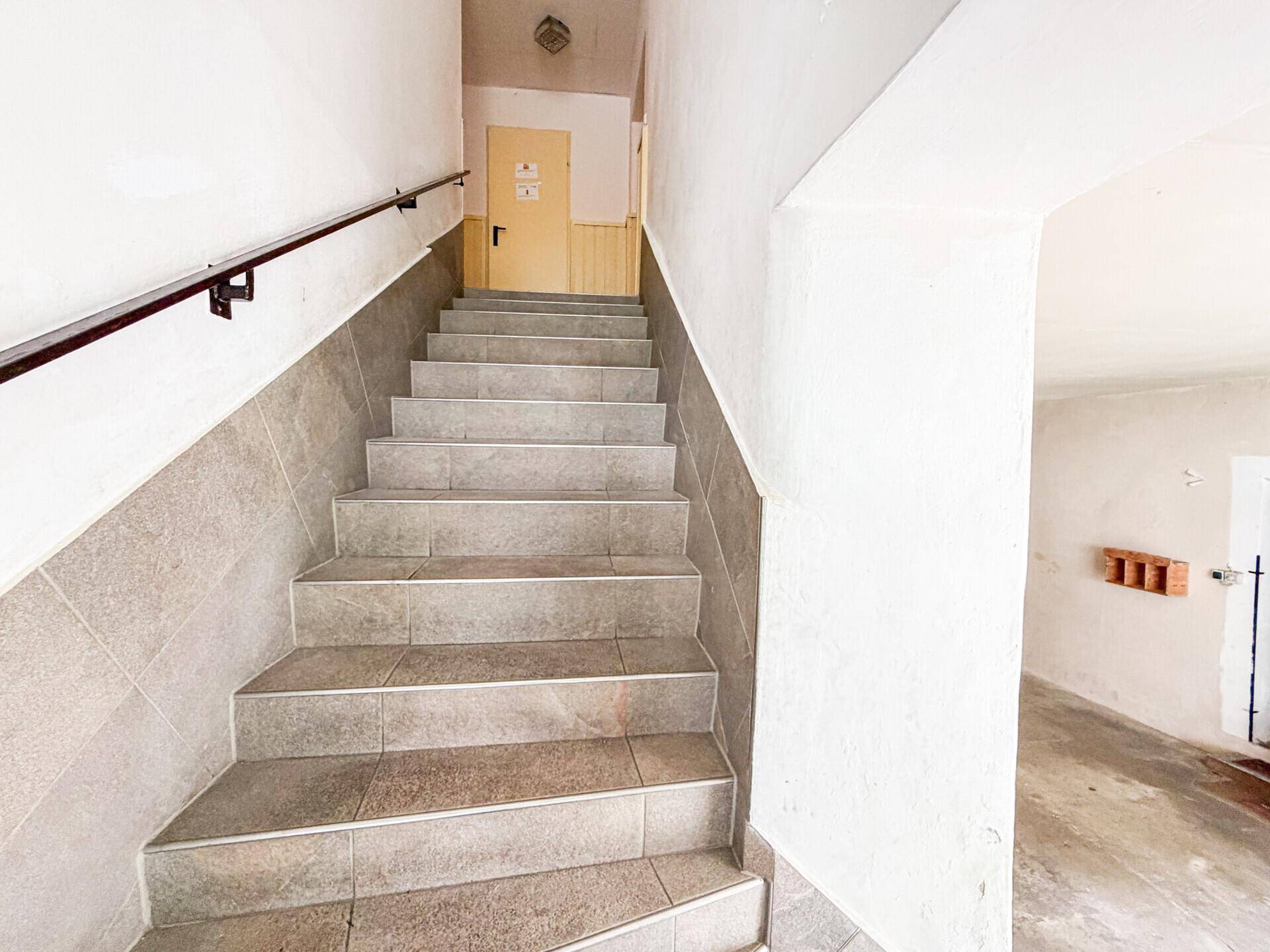 Gefliester Treppenaufgang mit Handlauf in einem Mehrfamilienhaus.
