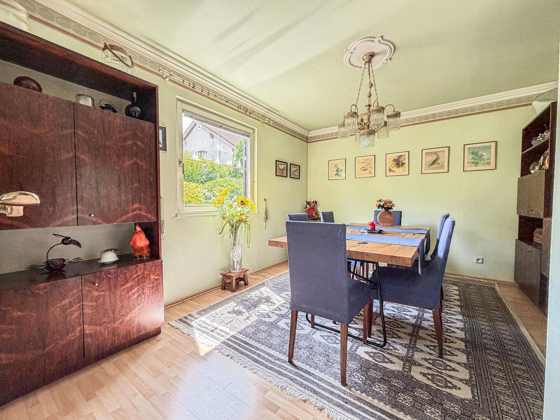 Klassisches Esszimmer mit Holztisch, blauen Stühlen und Stuckdecke.
