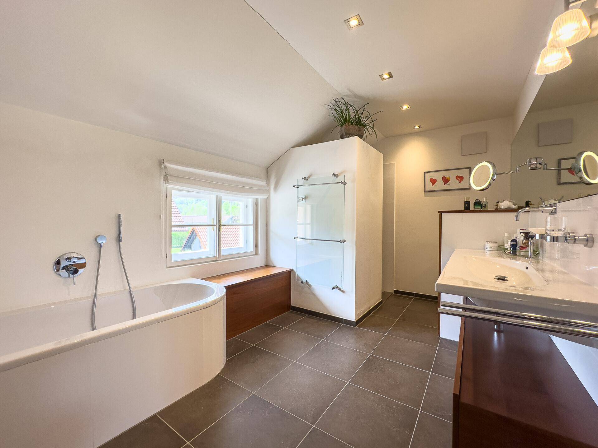 Modernes Badezimmer mit Badewanne, Doppelwaschbecken und Dachschräge.