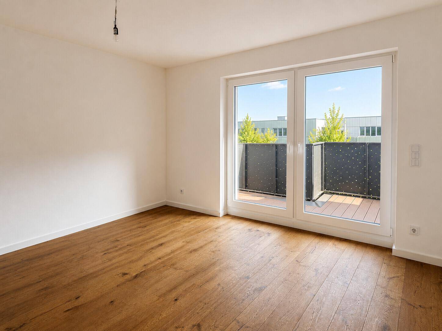 Lichtdurchflutetes Zimmer mit Holzboden und Balkonzugang, ideal für Wohnzwecke in einem Neubau.