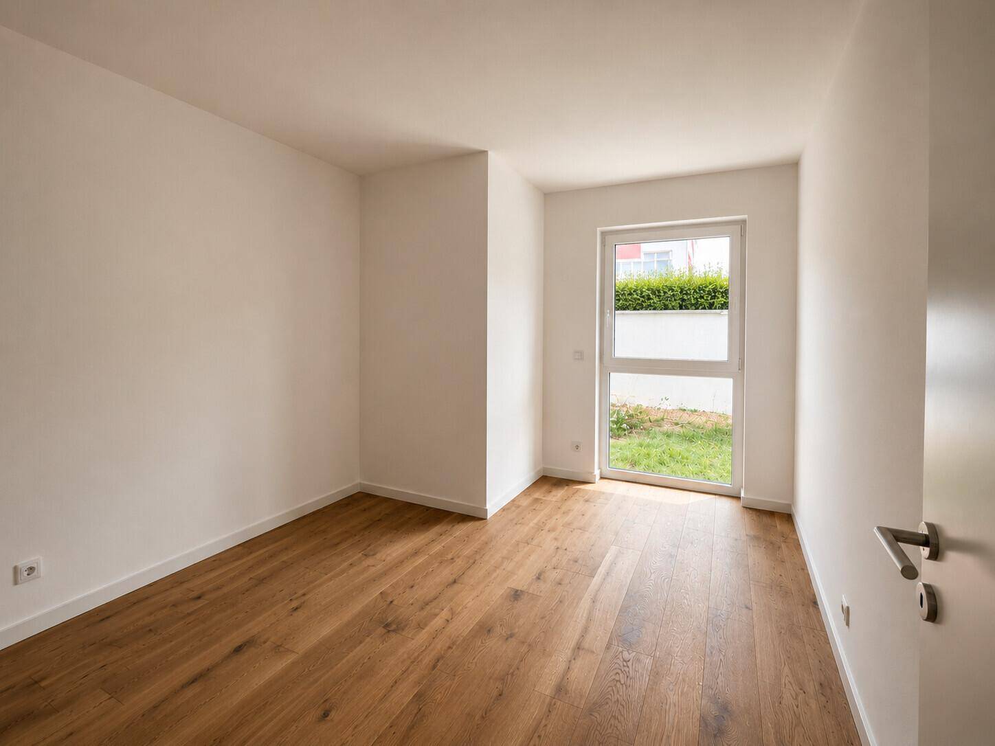 Helles Schlafzimmer mit Holzboden und direktem Zugang zu einem kleinen privaten Gartenbereich.