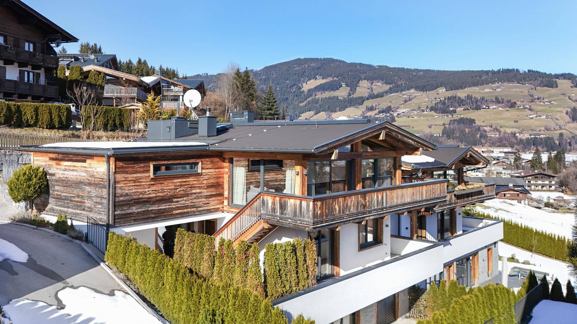 Attraktives Chalet im alpinen Stil mit Holzelementen und Balkonen in verschneiter Berglandschaft.