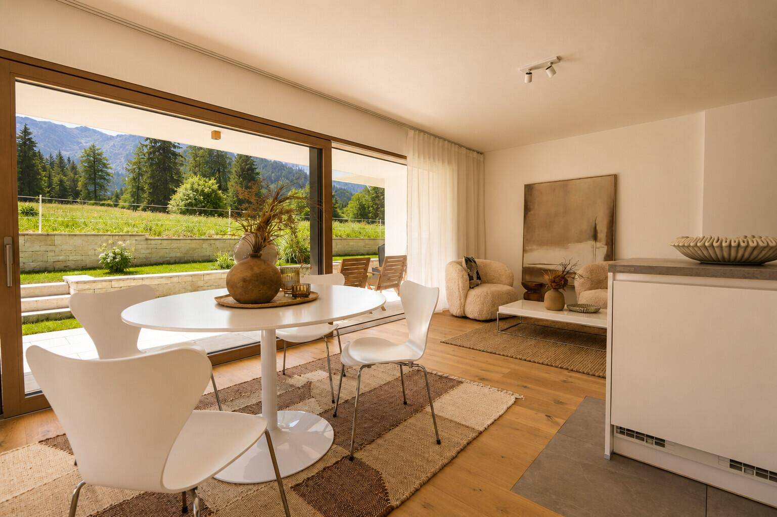 Heller Essbereich mit modernem runden Tisch und Stühlen, offen zum Wohnzimmer mit Bergblick.