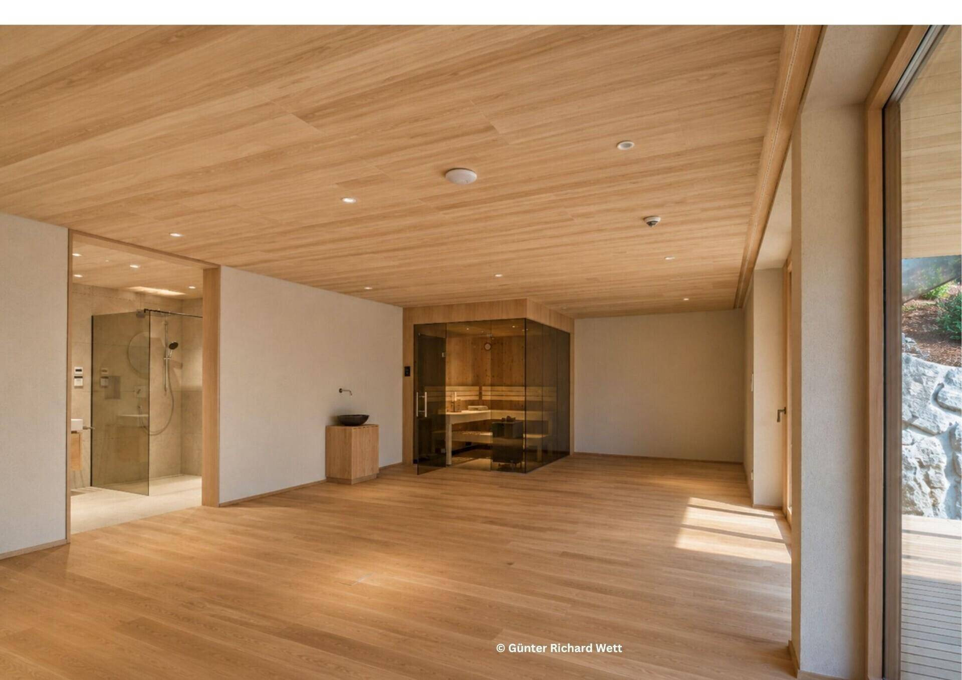 Geräumiger Wellnessbereich mit Sauna, begehbarer Dusche und Holzboden für Entspannung.