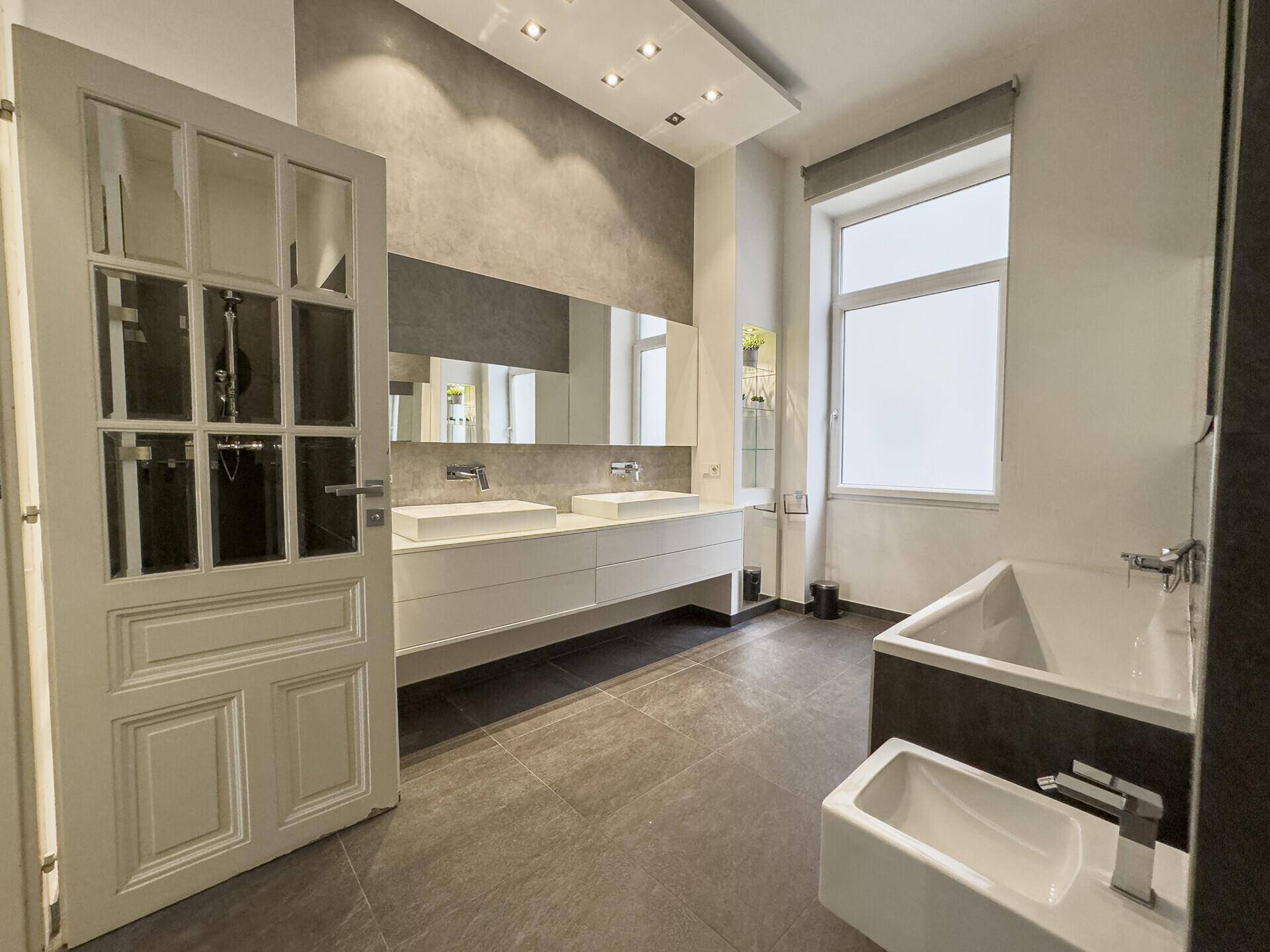 Elegantes Badezimmer mit Doppelwaschbecken, Badewanne und großer Dusche, ausgestattet mit modernen Armaturen.