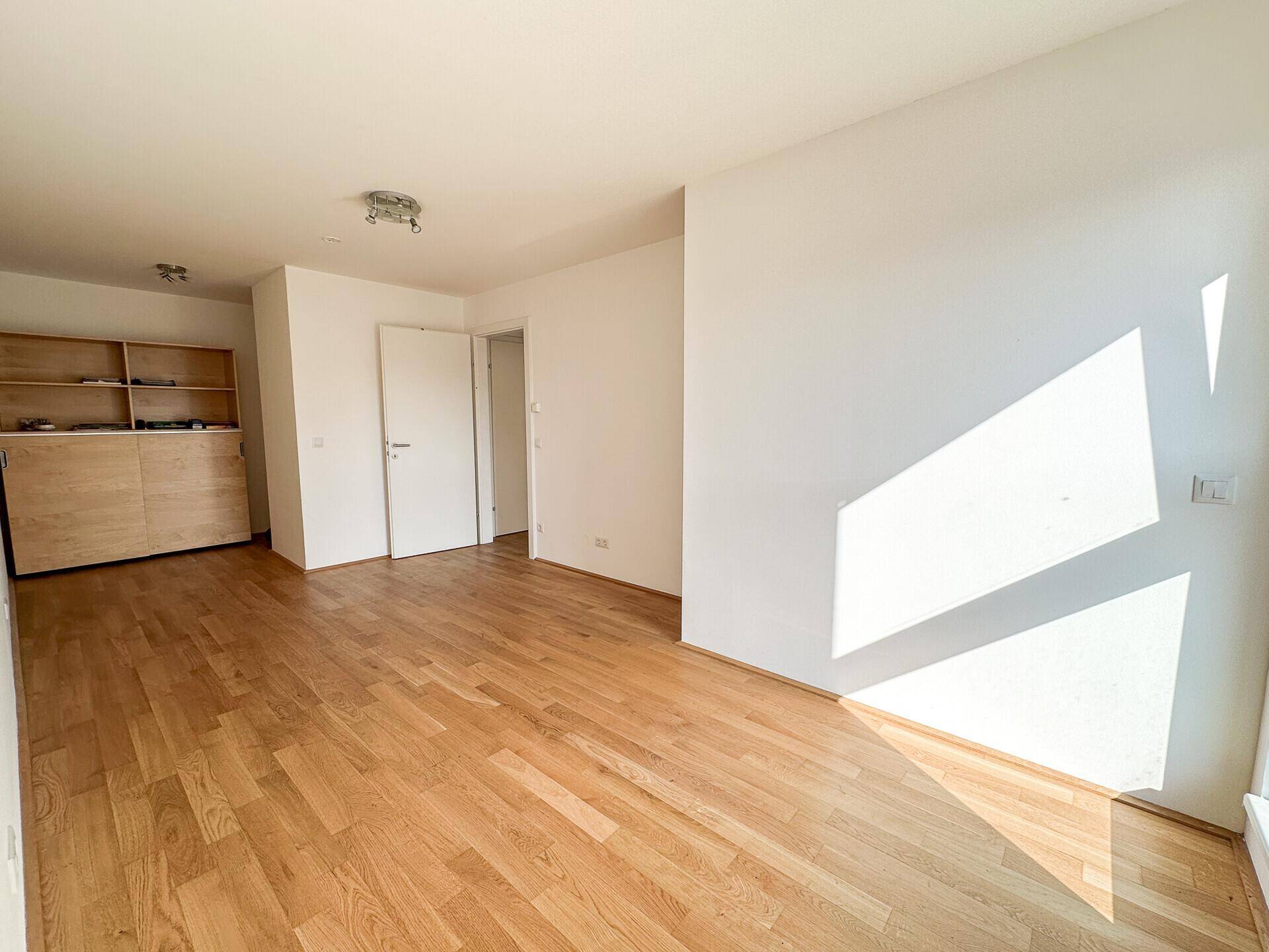 Heller Wohnbereich mit Holzboden und integriertem Holzregal, ideal für Stauraum.