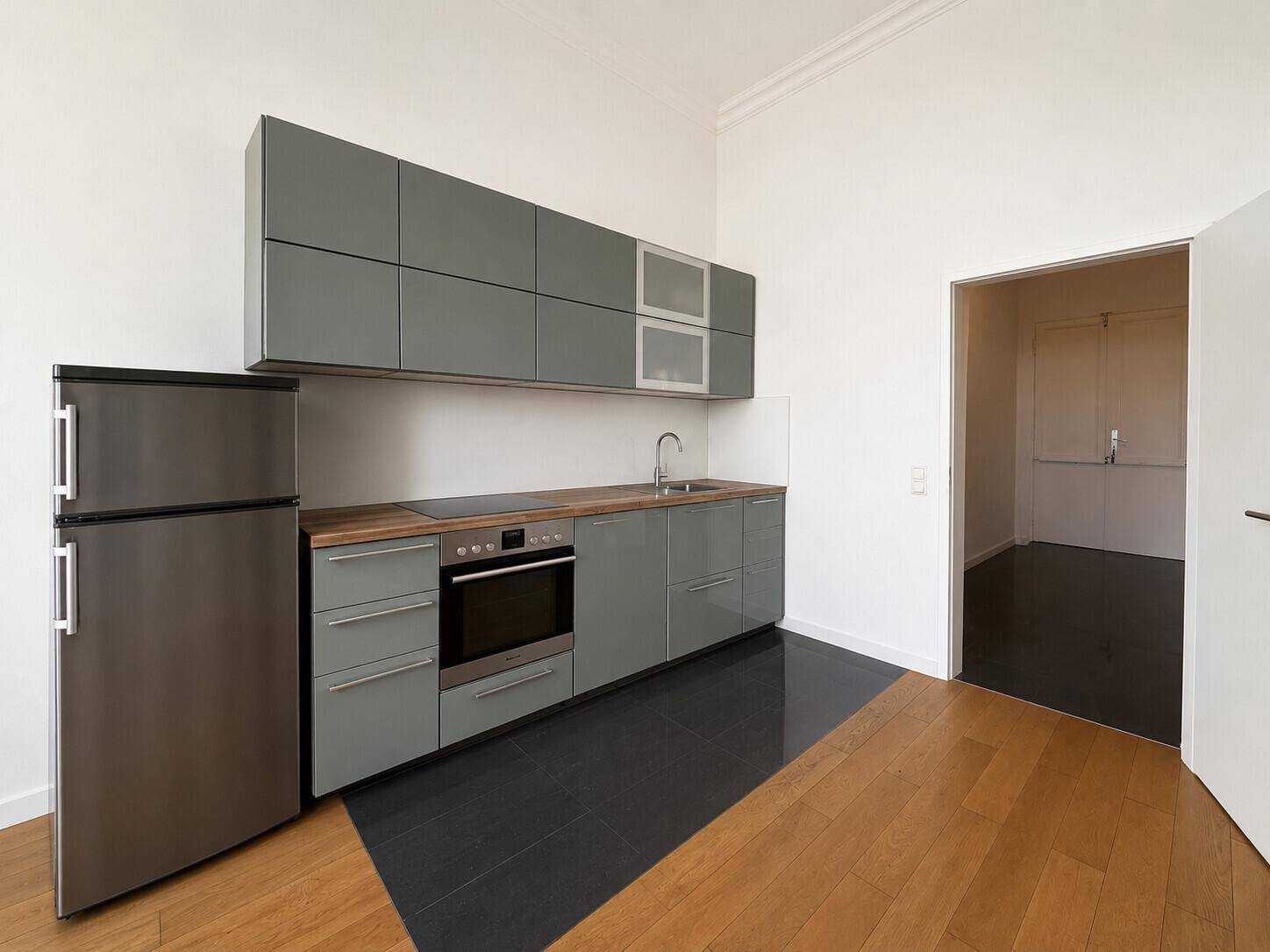 Moderne Küchenzeile mit grauen Schränken, Holz-Arbeitsplatte und integrierten Geräten.