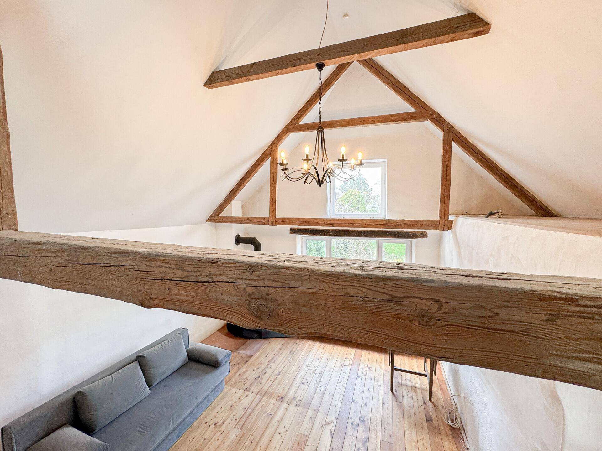 Offener Wohnbereich mit hohen Decken, sichtbaren Holzbalken und viel natürlichem Licht.