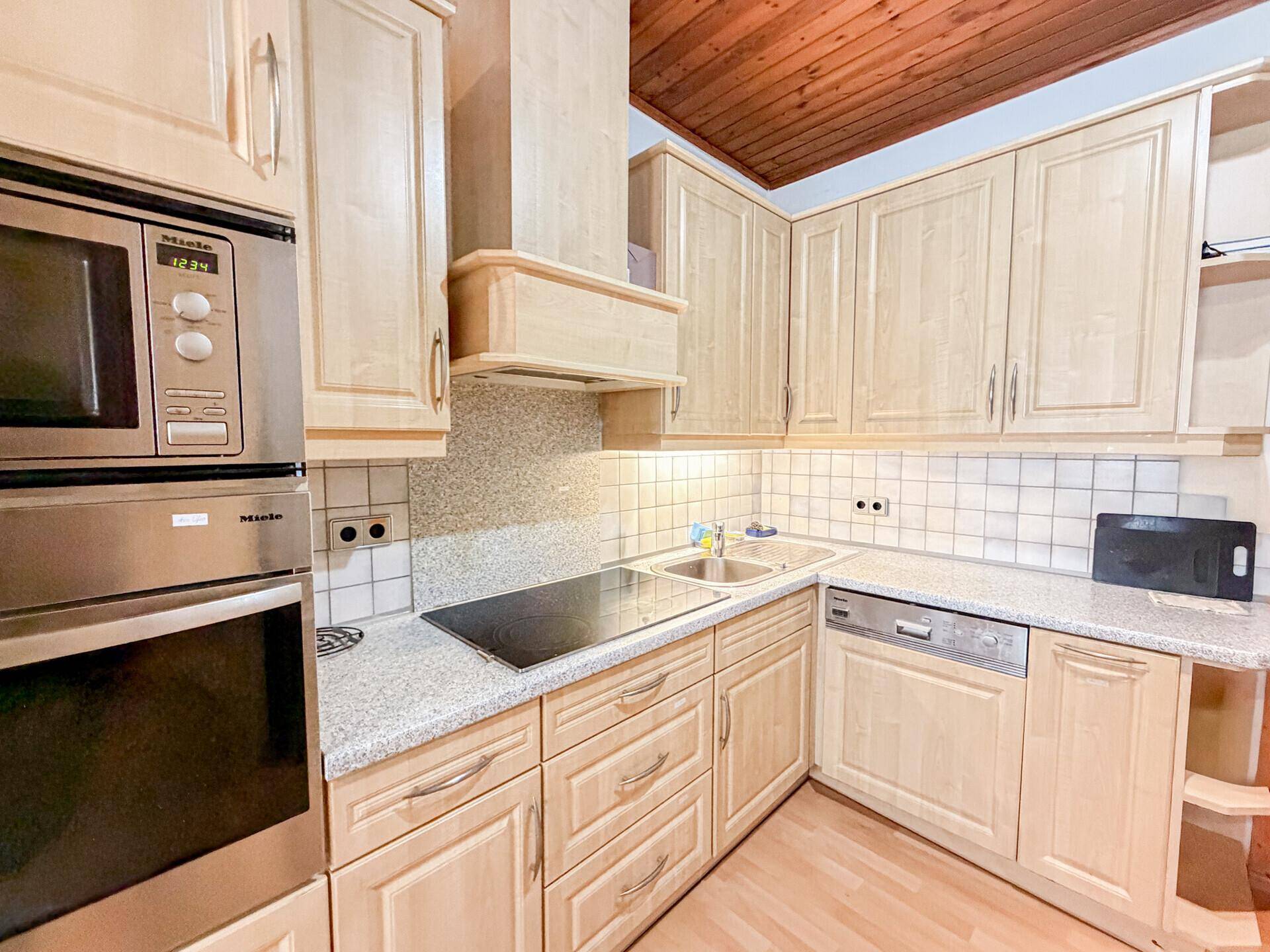 Moderne Küche mit hellen Holzschränken, Granitarbeitsplatte und Miele-Geräten.