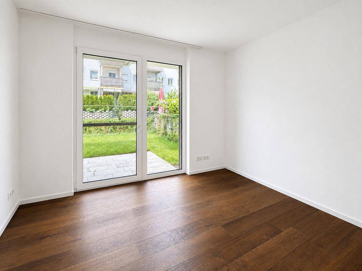 Helles Schlafzimmer mit Holzboden und direktem Zugang zum privaten Gartenbereich.
