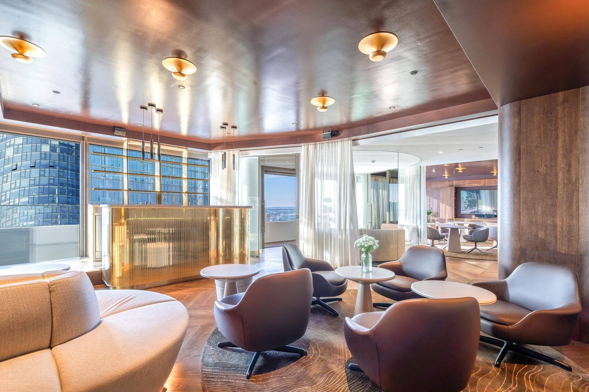 Exklusiver Loungebereich mit eleganter Bar, bequemen Sesseln und einem weiten Blick über die Stadt.