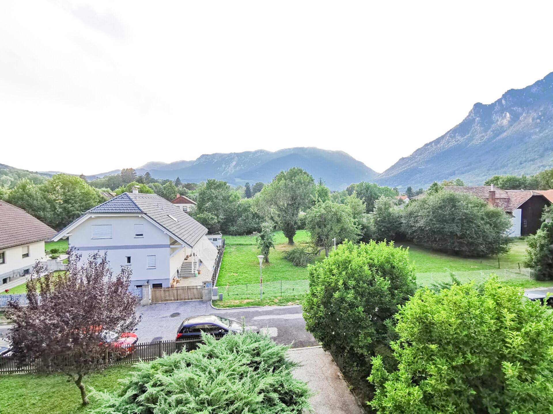 Weitläufiger Blick auf grüne Landschaft, Berge und umliegende Häuser.
