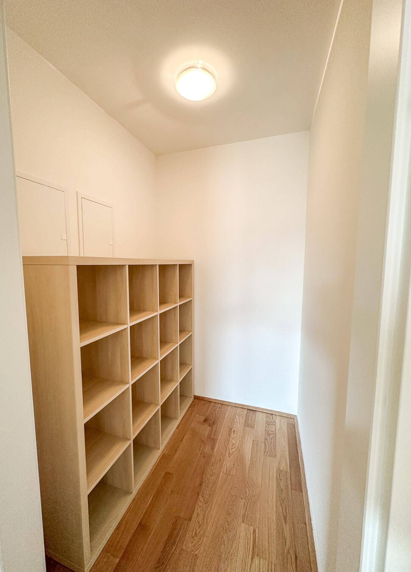 Praktischer Abstellraum mit Regalsystem und Holzboden für zusätzlichen Stauraum.