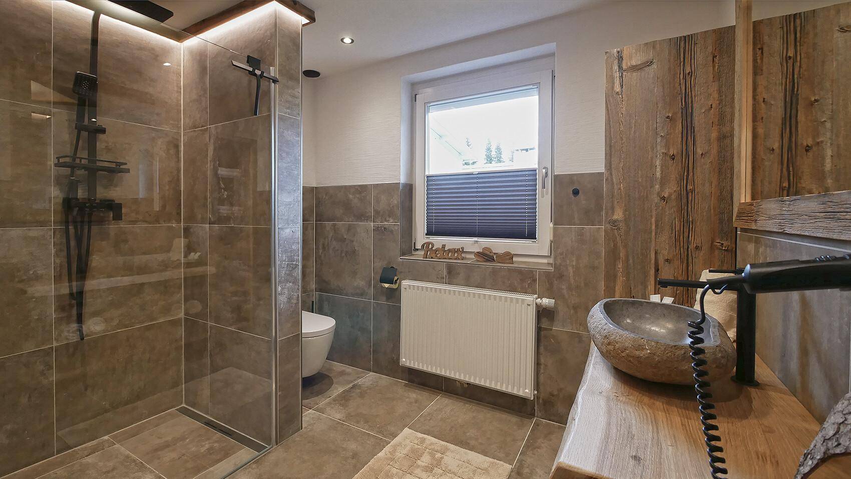 Modernes Badezimmer mit begehbarer Dusche, Natursteinwaschbecken und Fenster.