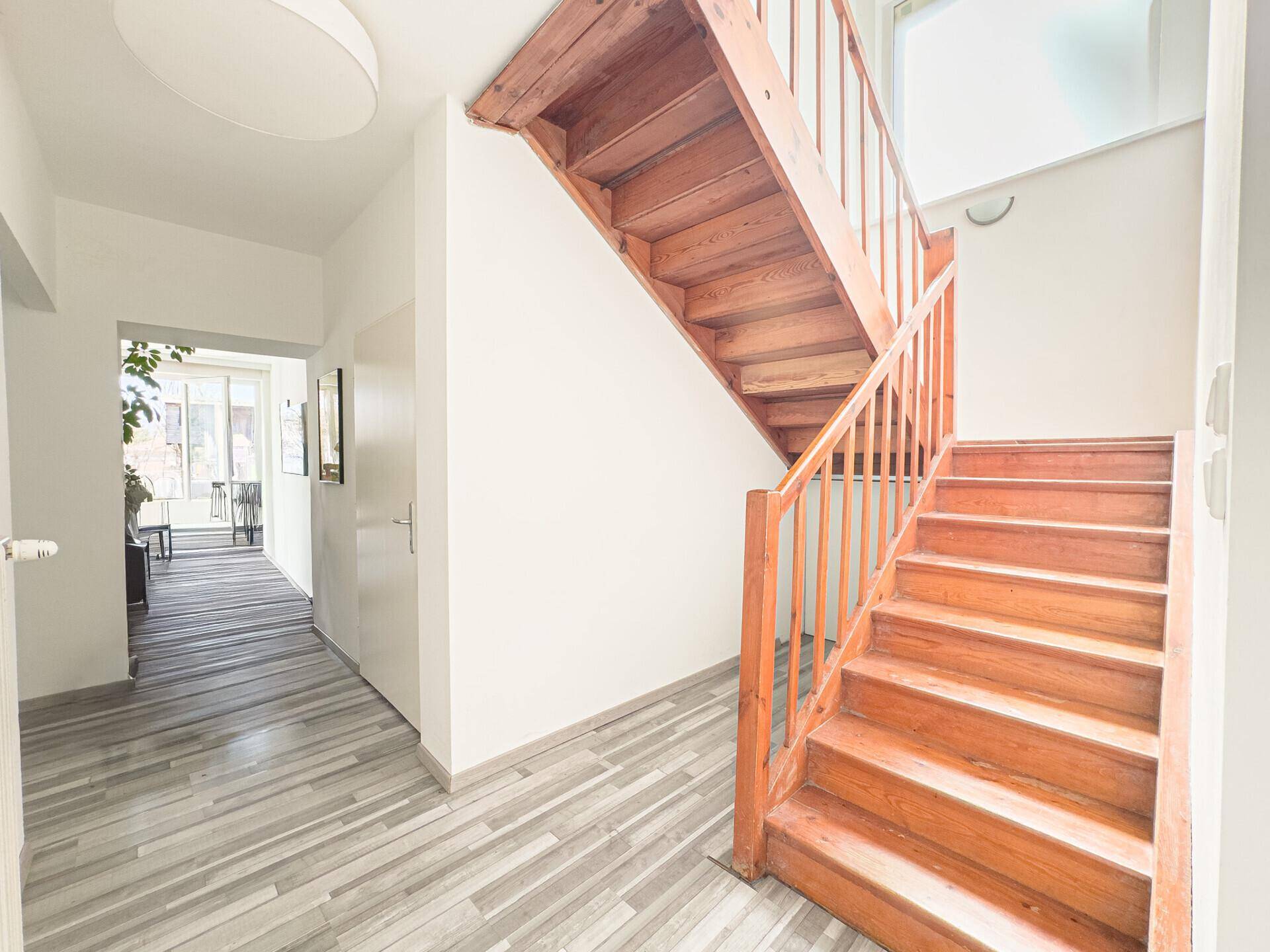 Geräumiger Flur mit Holztreppe, die in die obere Etage führt.