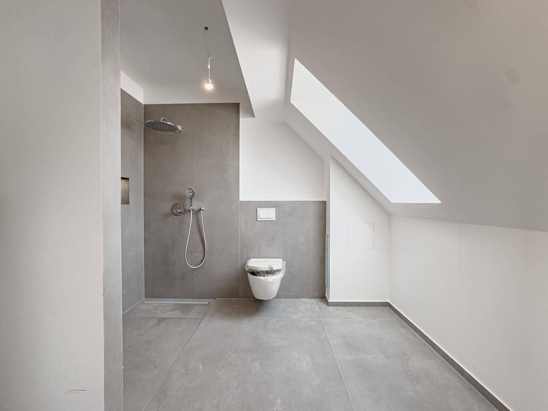 Modernes Badezimmer im Dachgeschoss mit ebenerdiger Dusche, Wand-WC und Dachfenster.