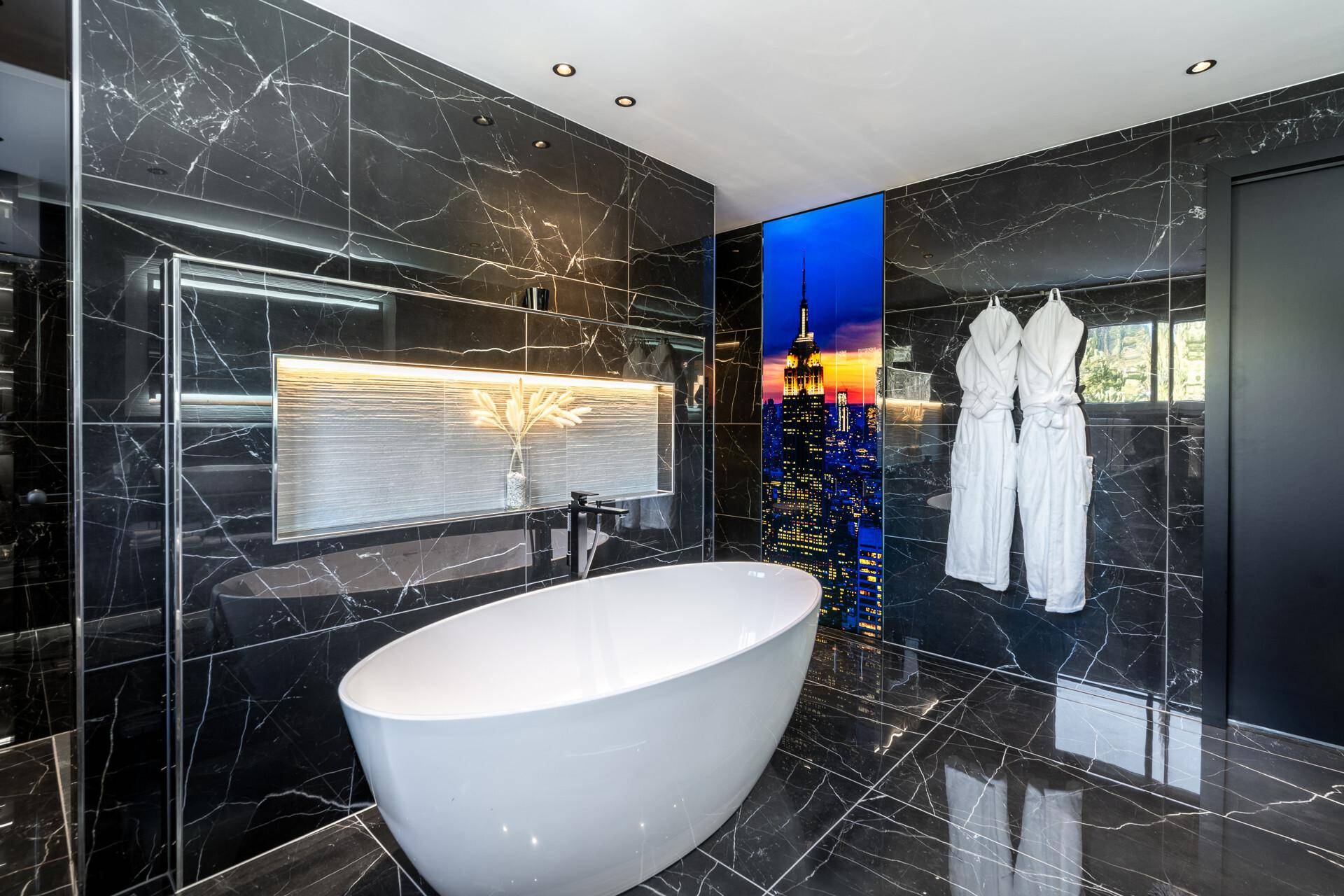 Luxuriöses Badezimmer mit schwarzem Marmor, freistehender Badewanne und moderner Beleuchtung.