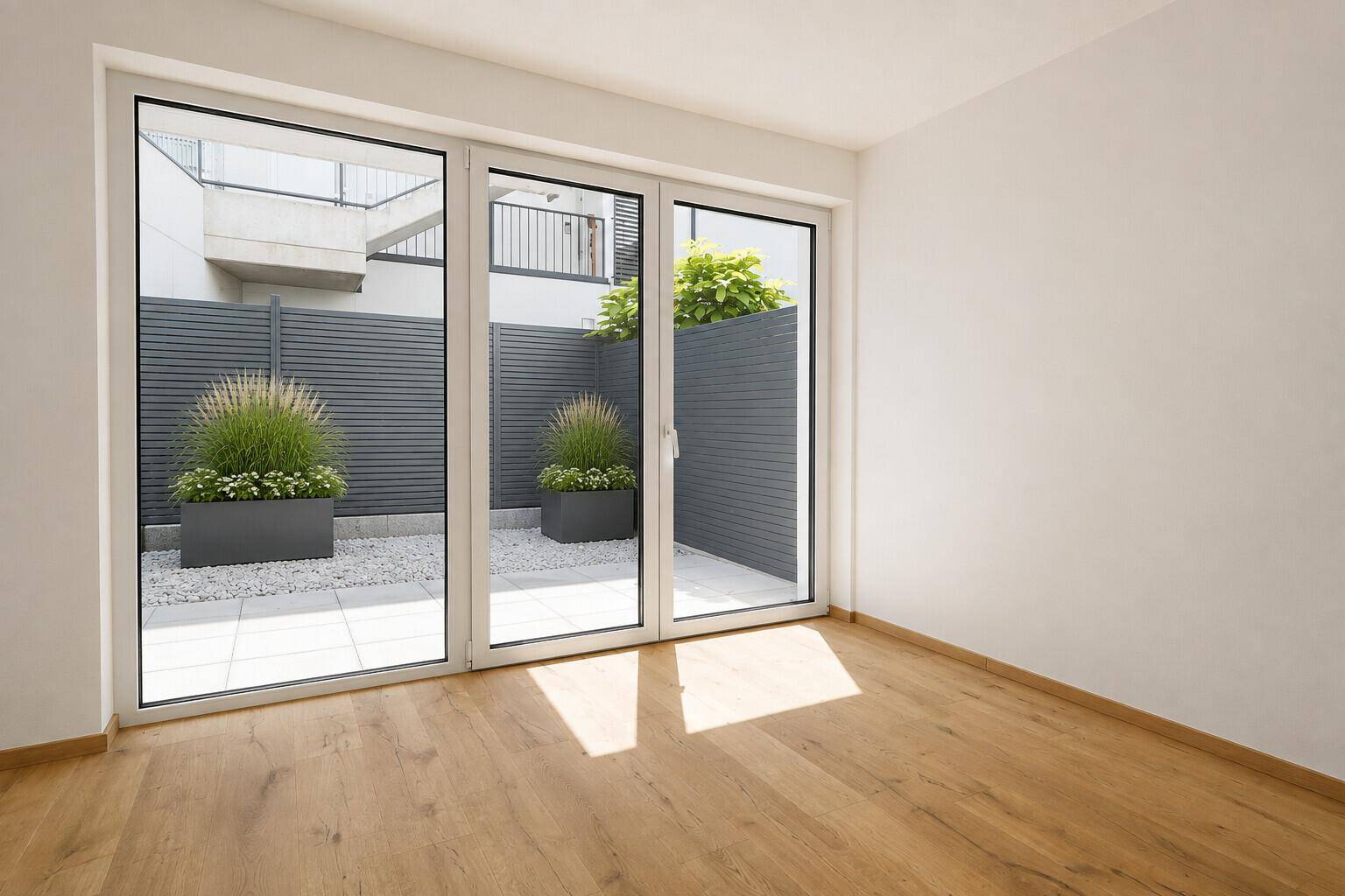 Heller Raum mit Holzboden und großen Glasschiebetüren, die zu einem privaten Außenbereich führen.