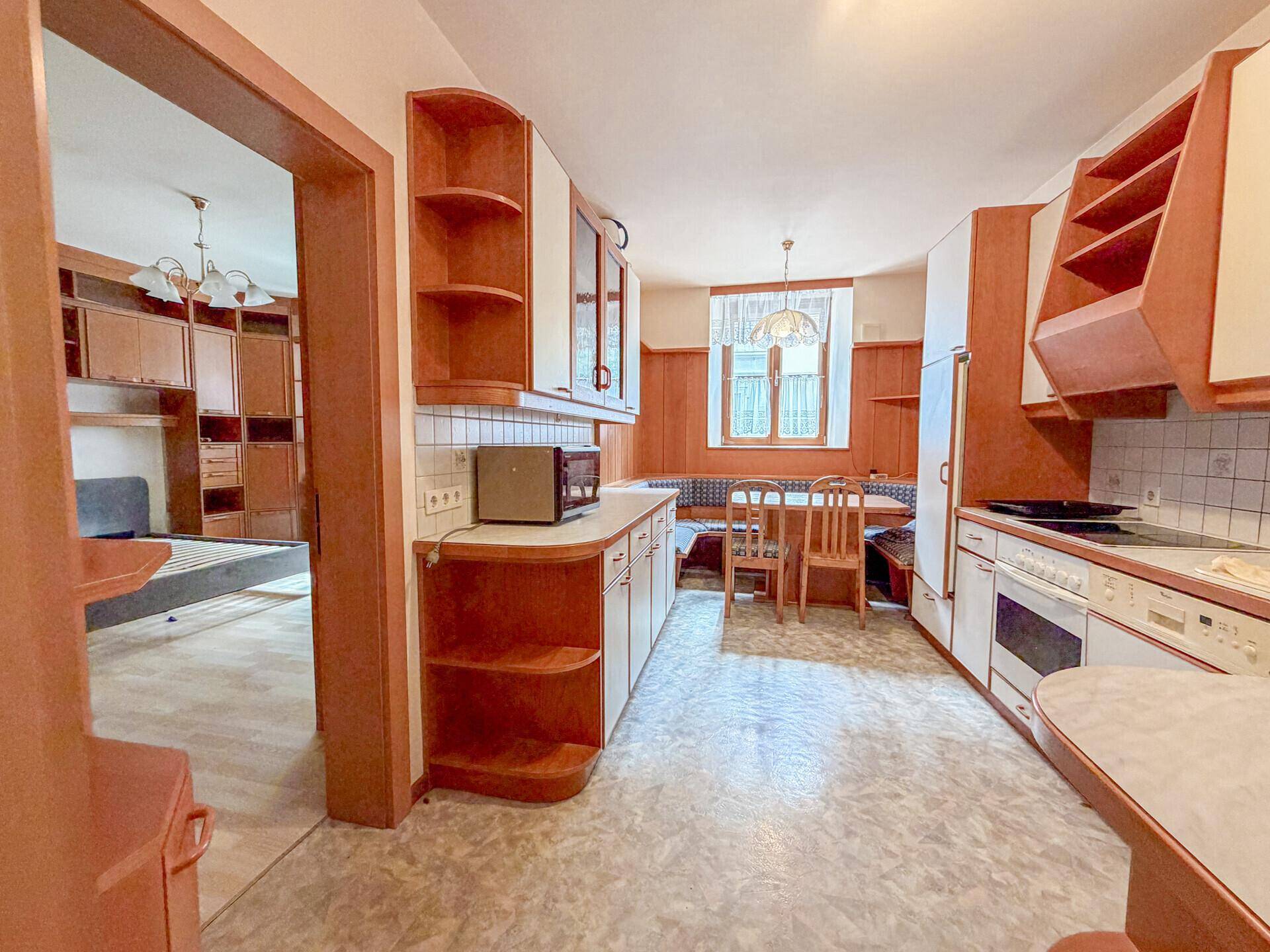 Traditionelle Wohnküche mit Essbereich und Blick in ein angrenzendes Zimmer.